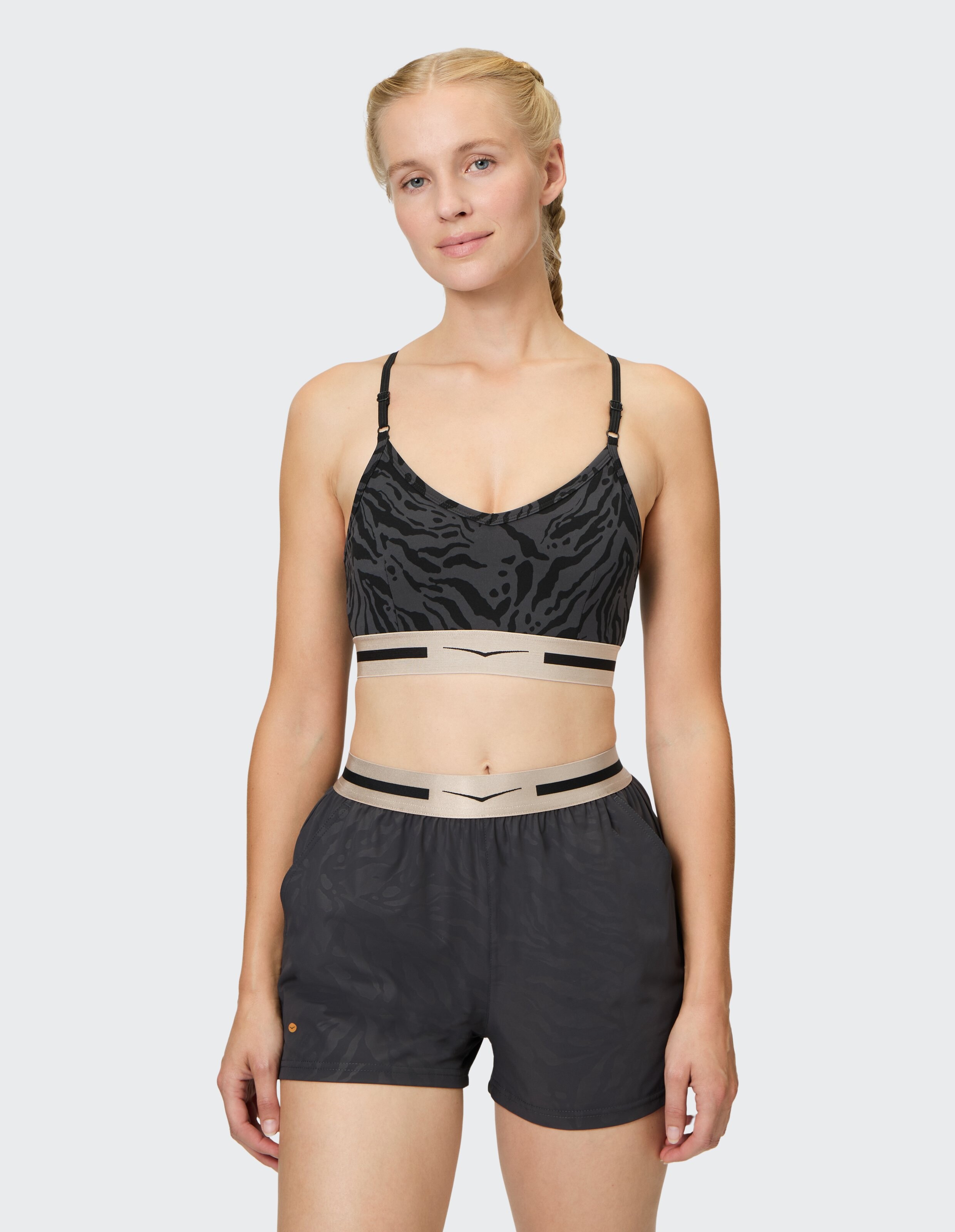 Frau trägt einen schwarzen Sport-BH mit Animal-Print und passende lässige Lounge-Shorts.
