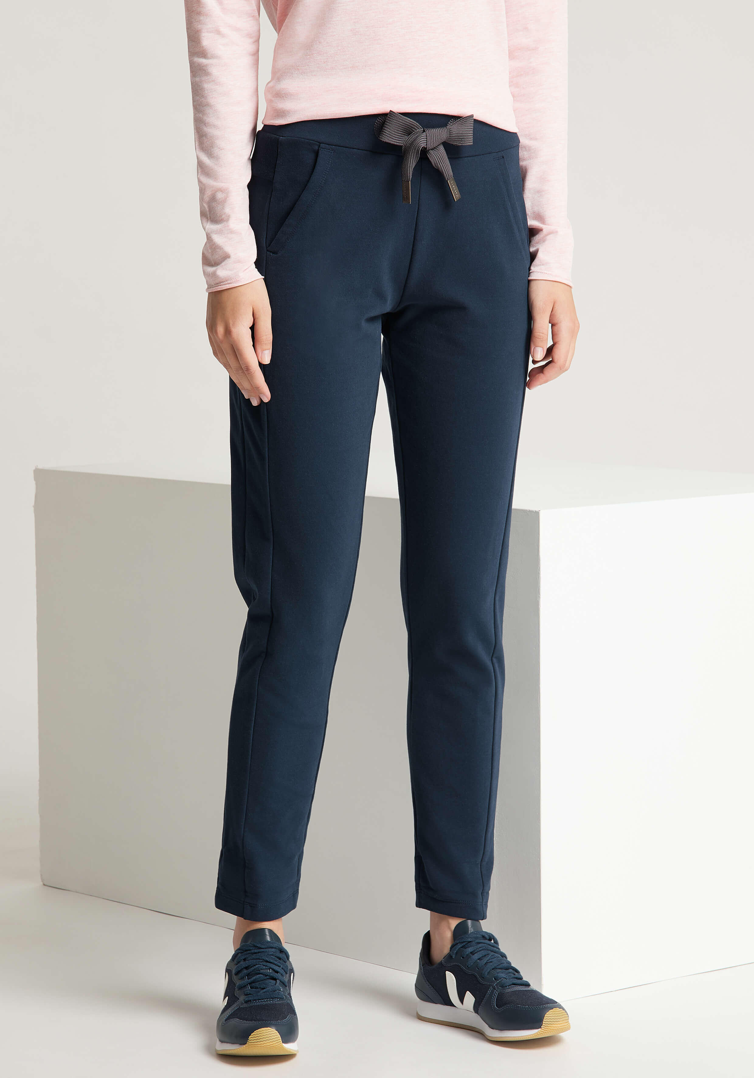 Frau trägt dunkelblaue, lässige Jogginghose mit Kordelzug in der Taille für bequeme Loungewear.