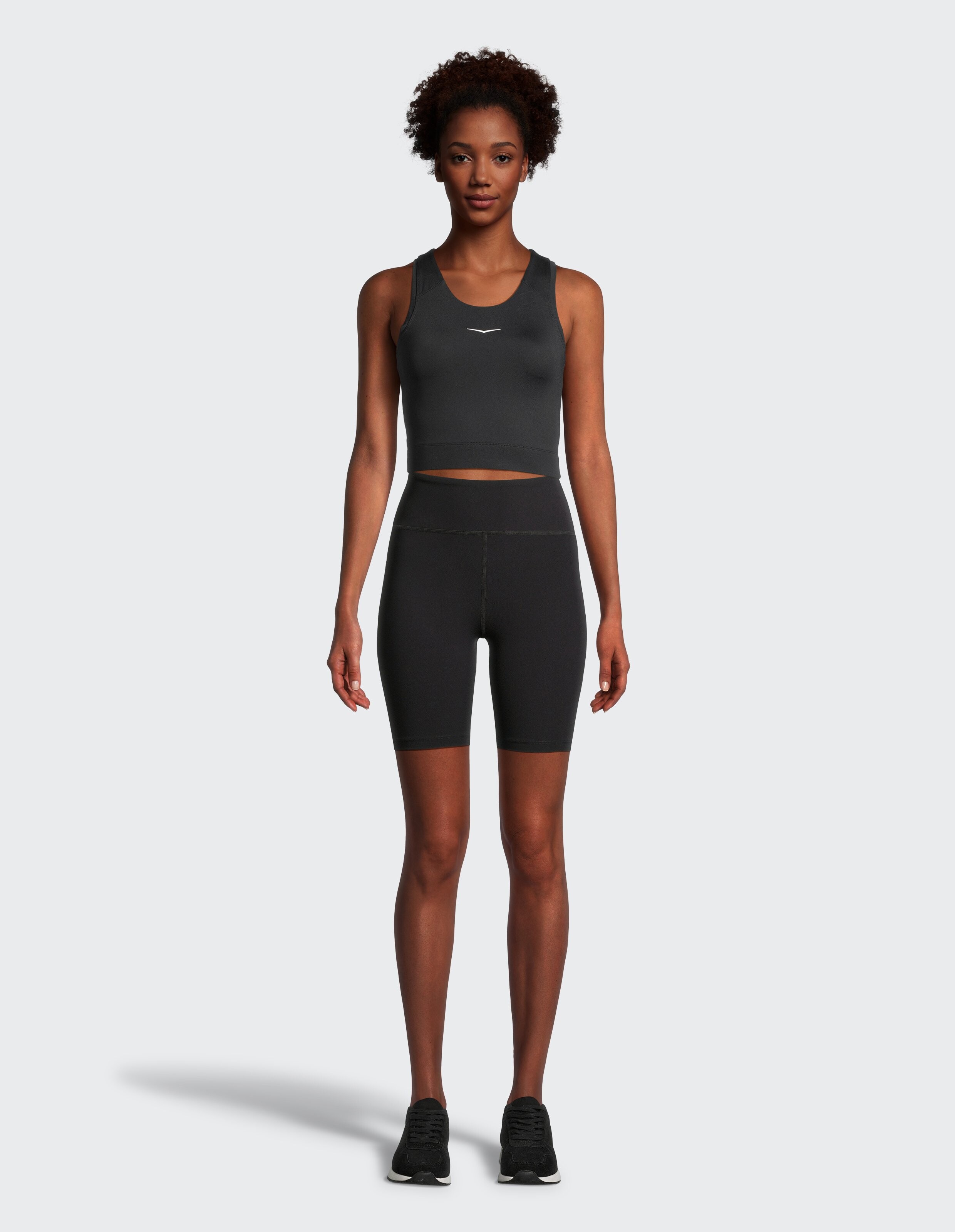Das Model trägt ein schwarzes, kurzes Tanktop und passende Shorts mit hoher Taille.