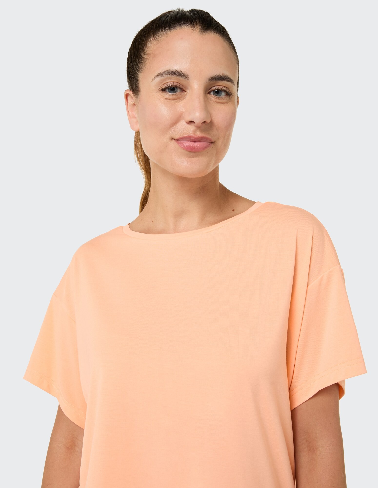Frau trägt ein weiches, pfirsichfarbenes, übergroßes T-Shirt, perfekt für Freizeitausflüge.