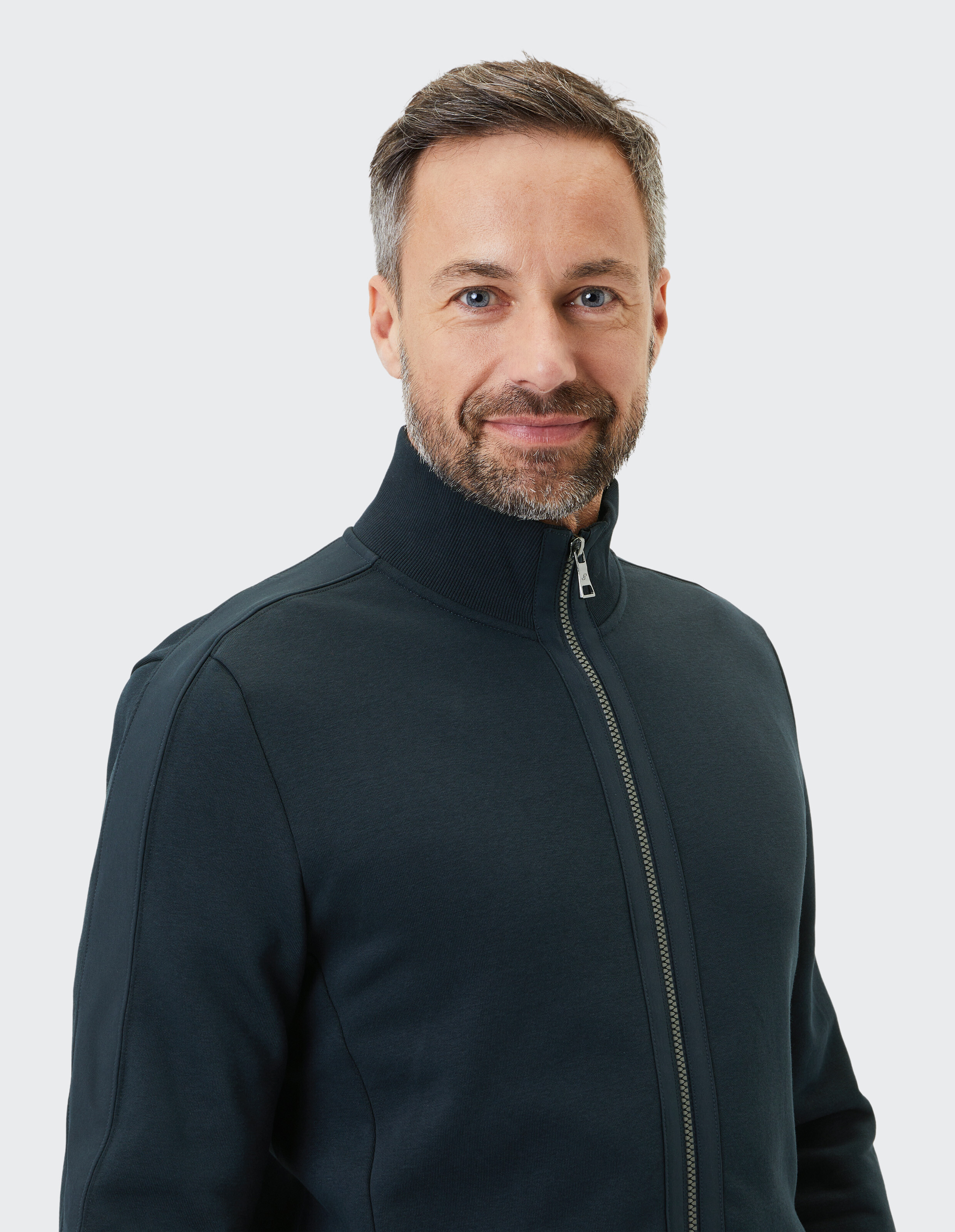Mann trägt ein dunkelblaues Sweatshirt mit Stehkragen und Reißverschluss für lässigen Komfort.