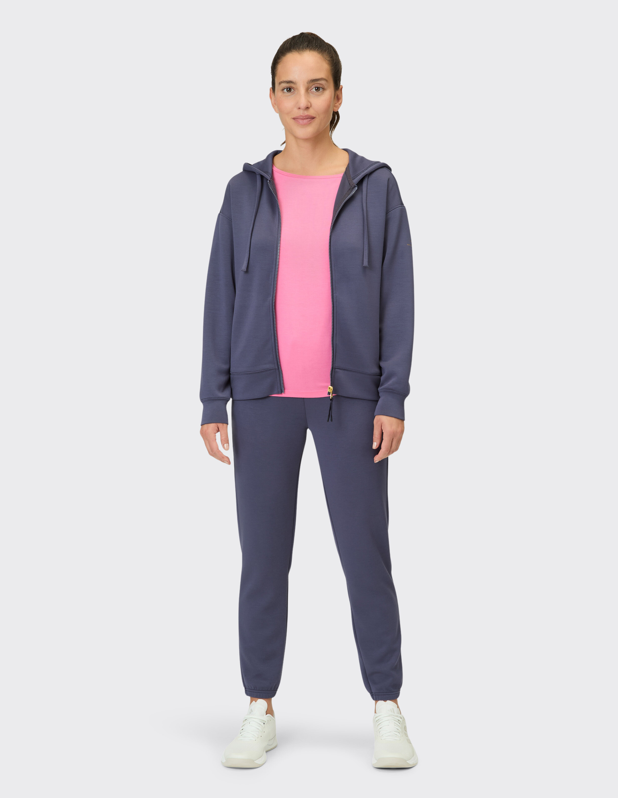 Frau in gemütlichem marineblauem Kapuzenpullover und Jogginghose mit rosafarbenem Oberteil, perfekt für Freizeitkleidung.