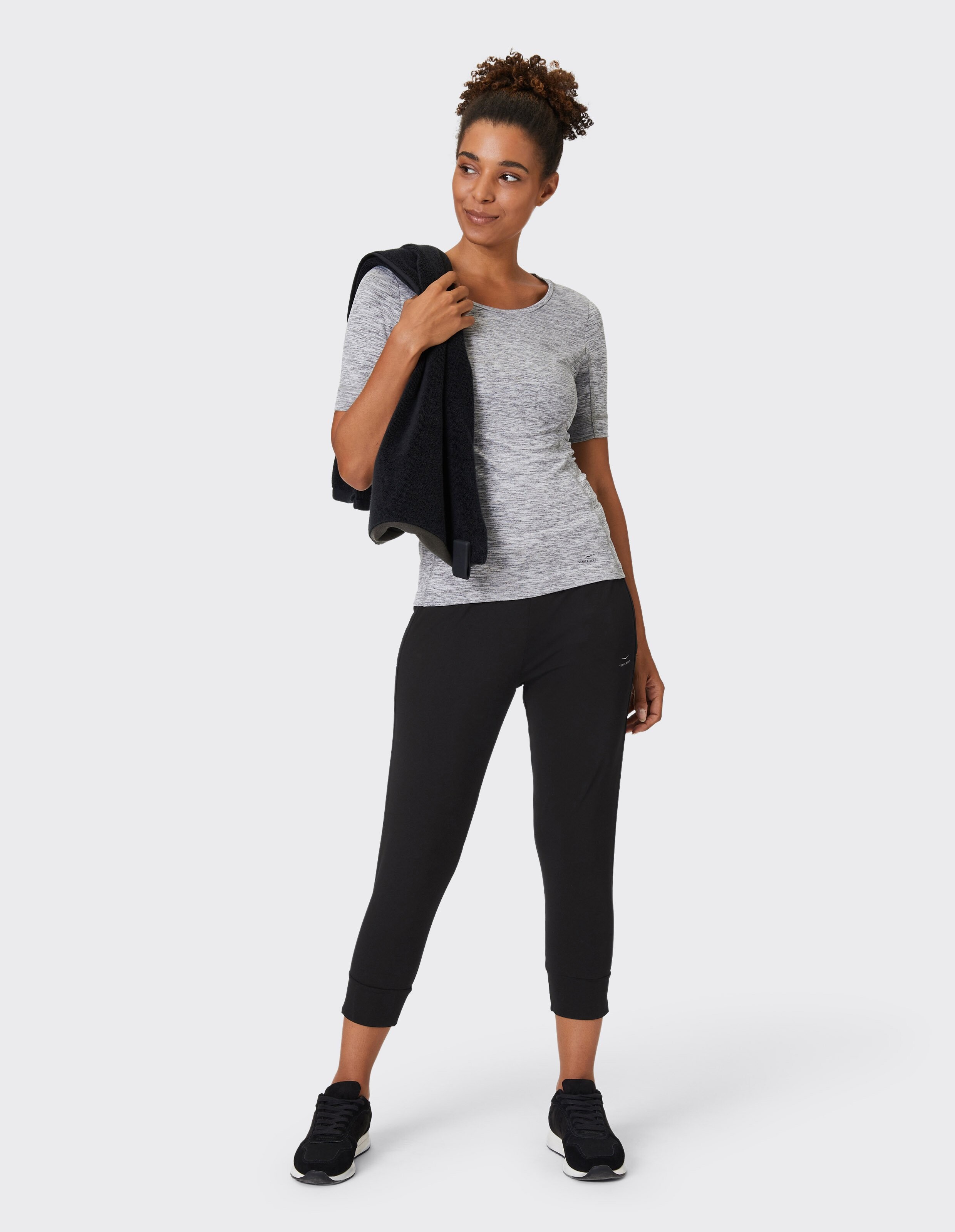 Frau trägt ein grau meliertes T-Shirt und eine schwarze Loungehose für einen lässigen Look.