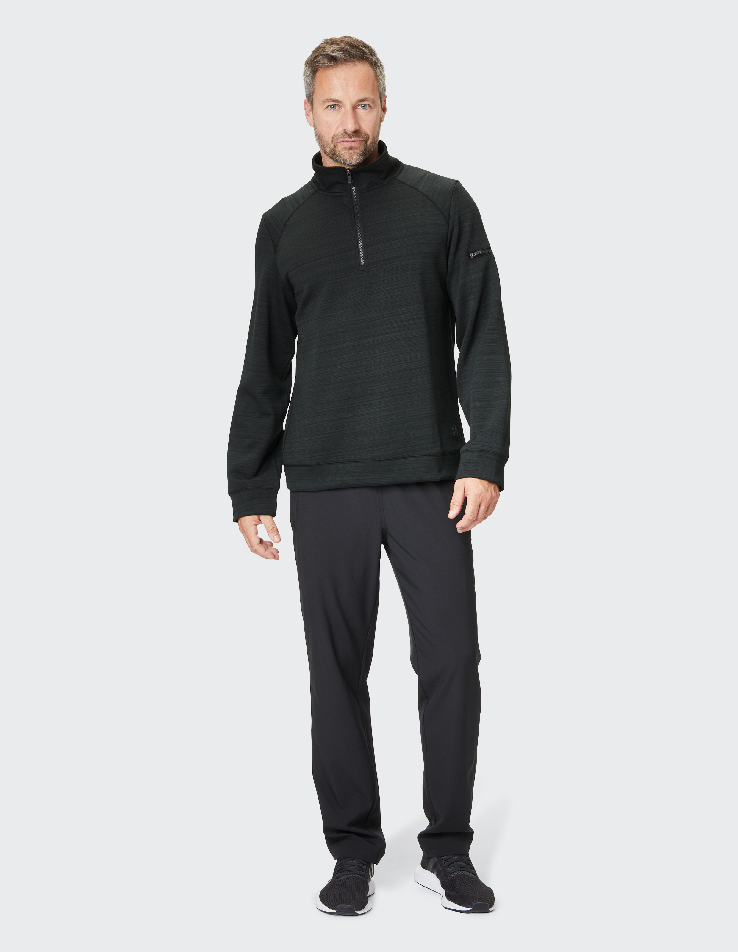 Schwarzer Herrenpullover mit halbem Reißverschluss und schwarze Hose, perfekt für Freizeitkleidung.
