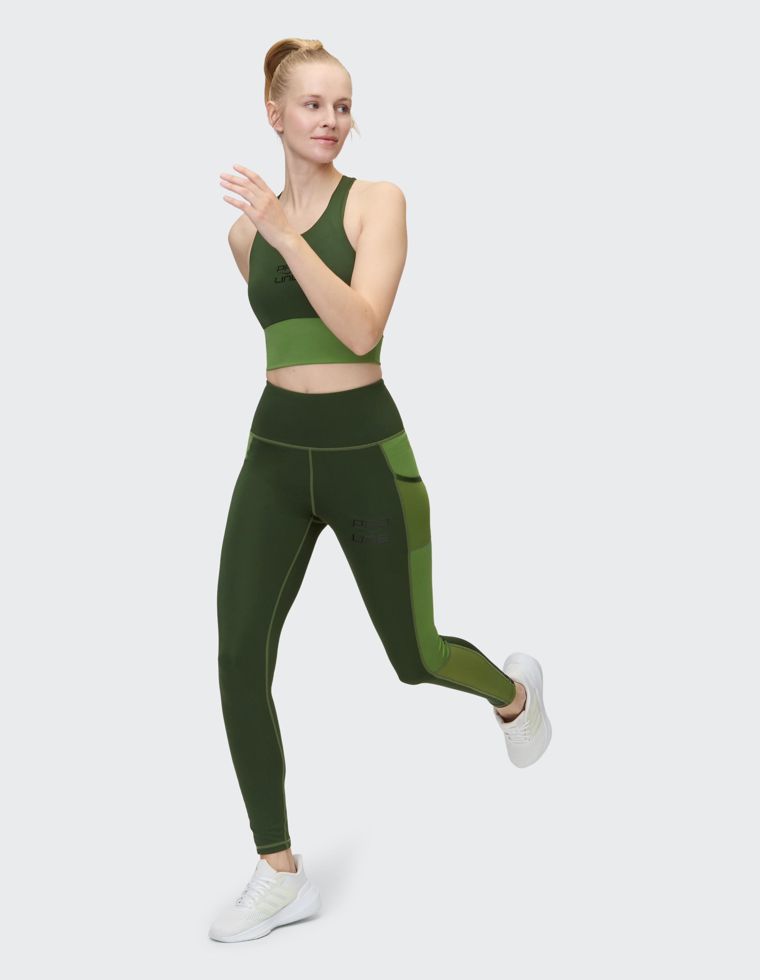 Modell in grünem Sport-BH und Leggings, ideal für aktive Freizeitkleidung.