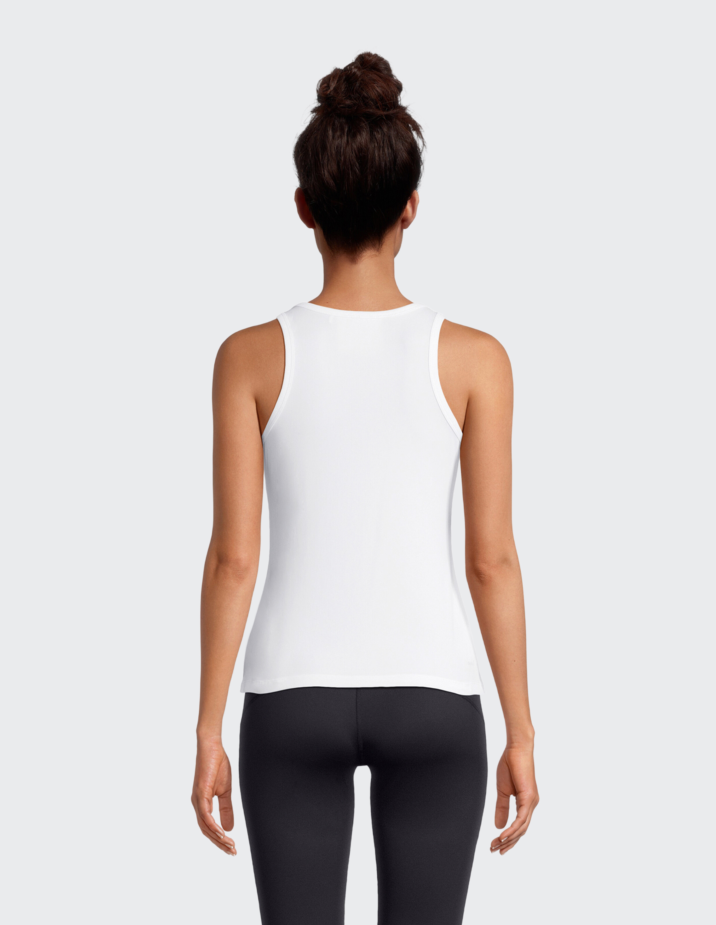 Rückansicht einer Frau in einem weißen Tanktop und schwarzen Leggings, die einen lässigen Stil unterstreicht.