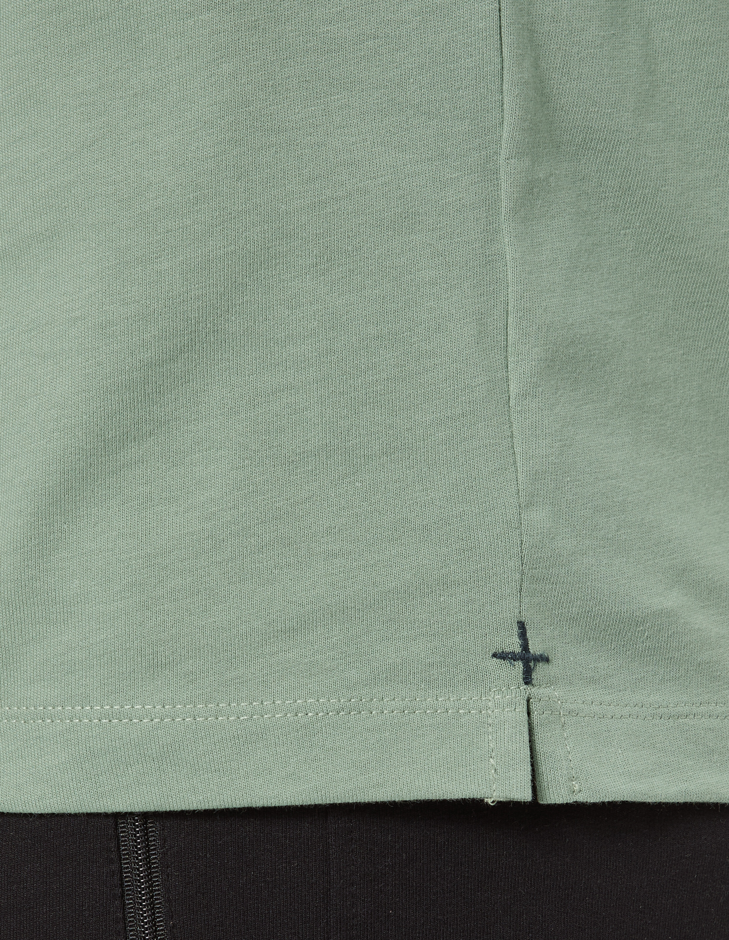 Nahaufnahme eines hellgrünen Freizeit-T-Shirts mit einzigartigem Saumdetail.