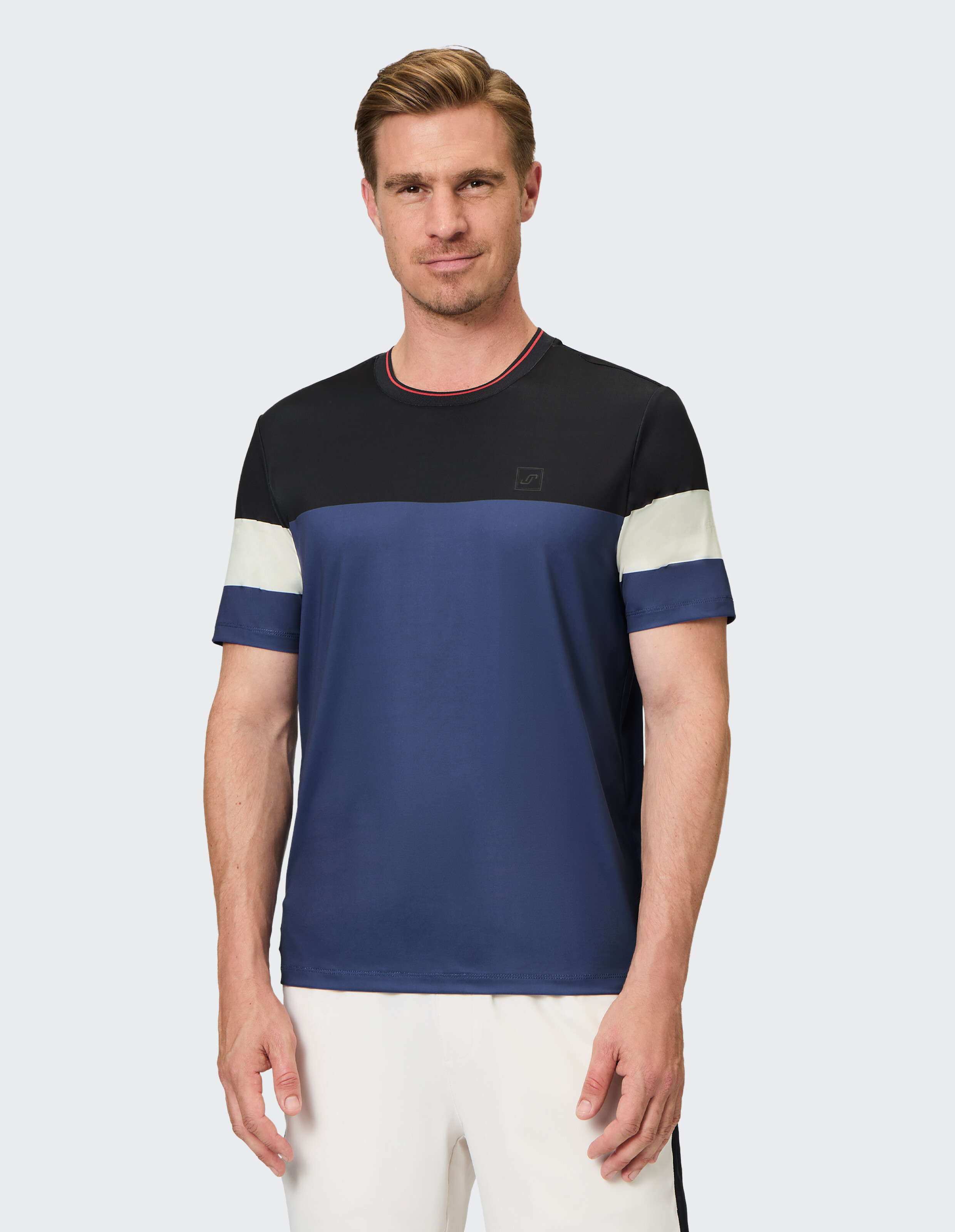 Mann trägt ein lässiges Farbblock-T-Shirt mit schwarzen, blauen und weißen Streifen.