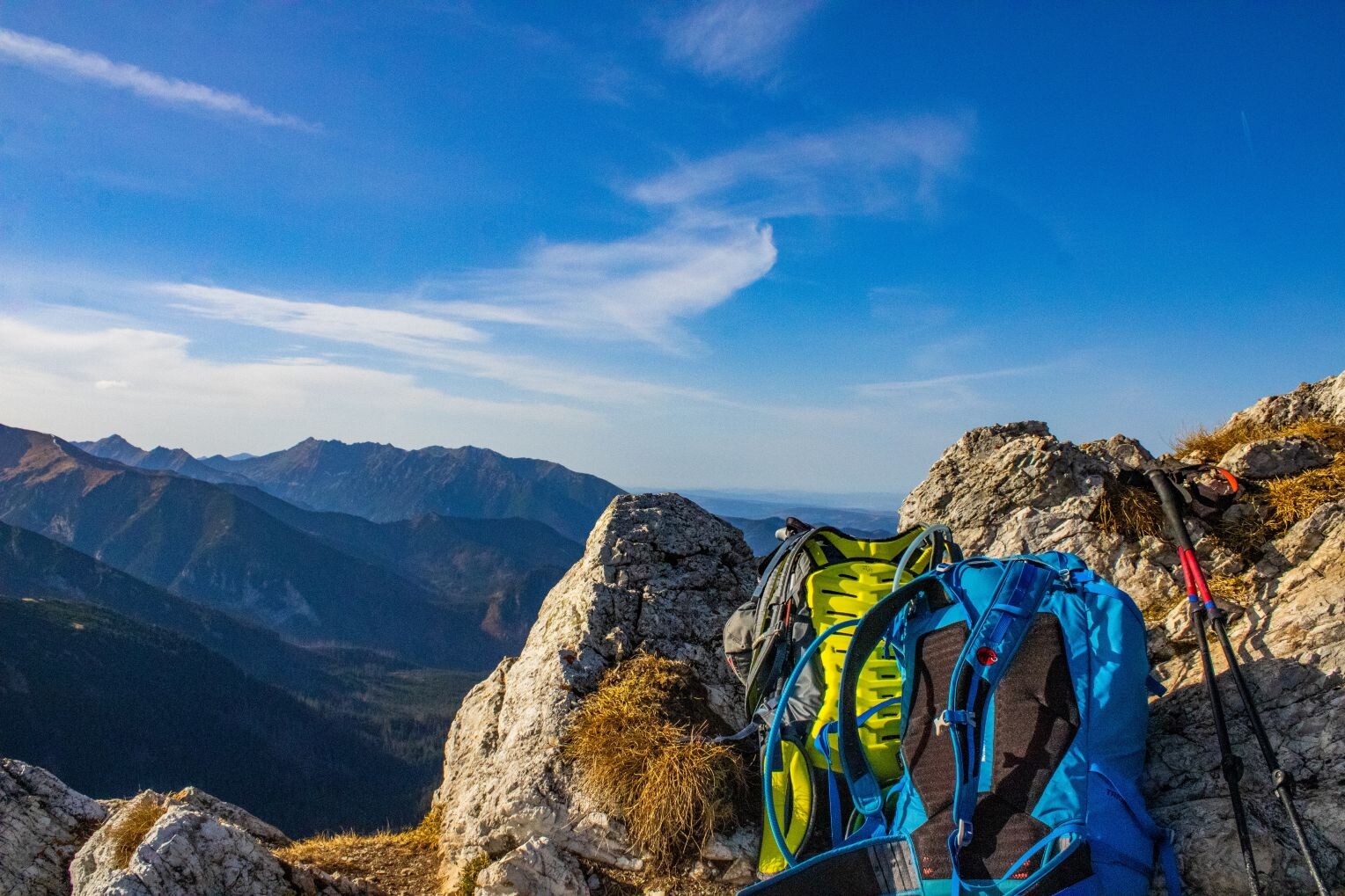 Bunte Wanderrucksäcke auf felsigem Gelände mit Bergkulisse.