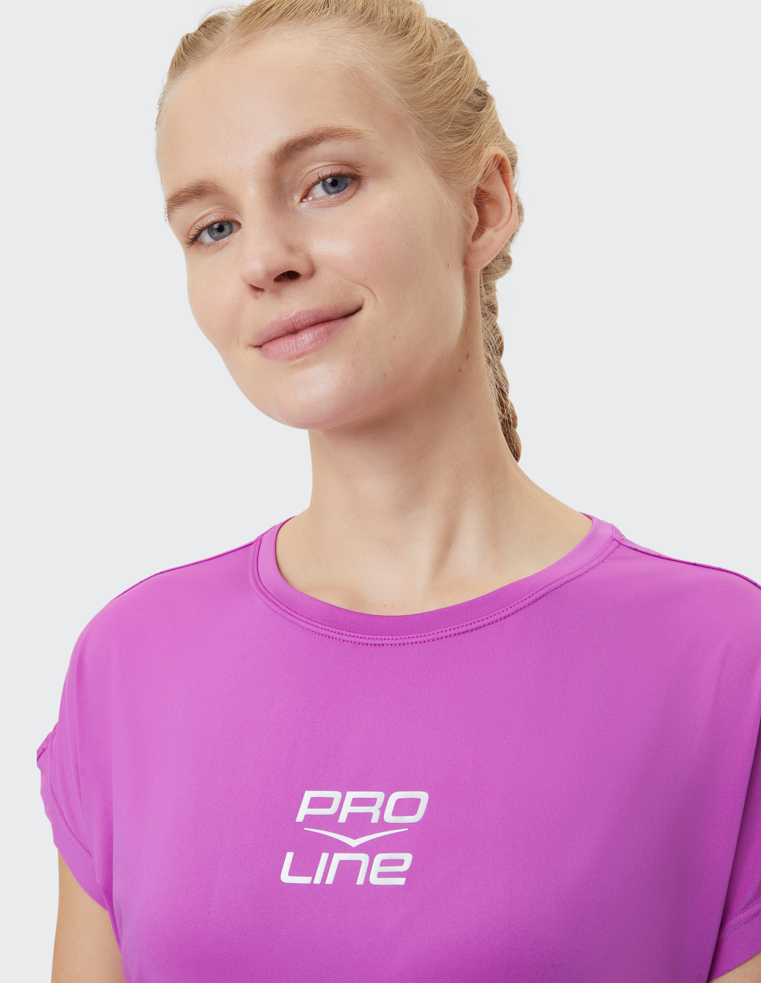 Nahaufnahme einer Frau, die ein rosa PRO LINE-T-Shirt trägt und einen lässigen Stil unterstreicht.