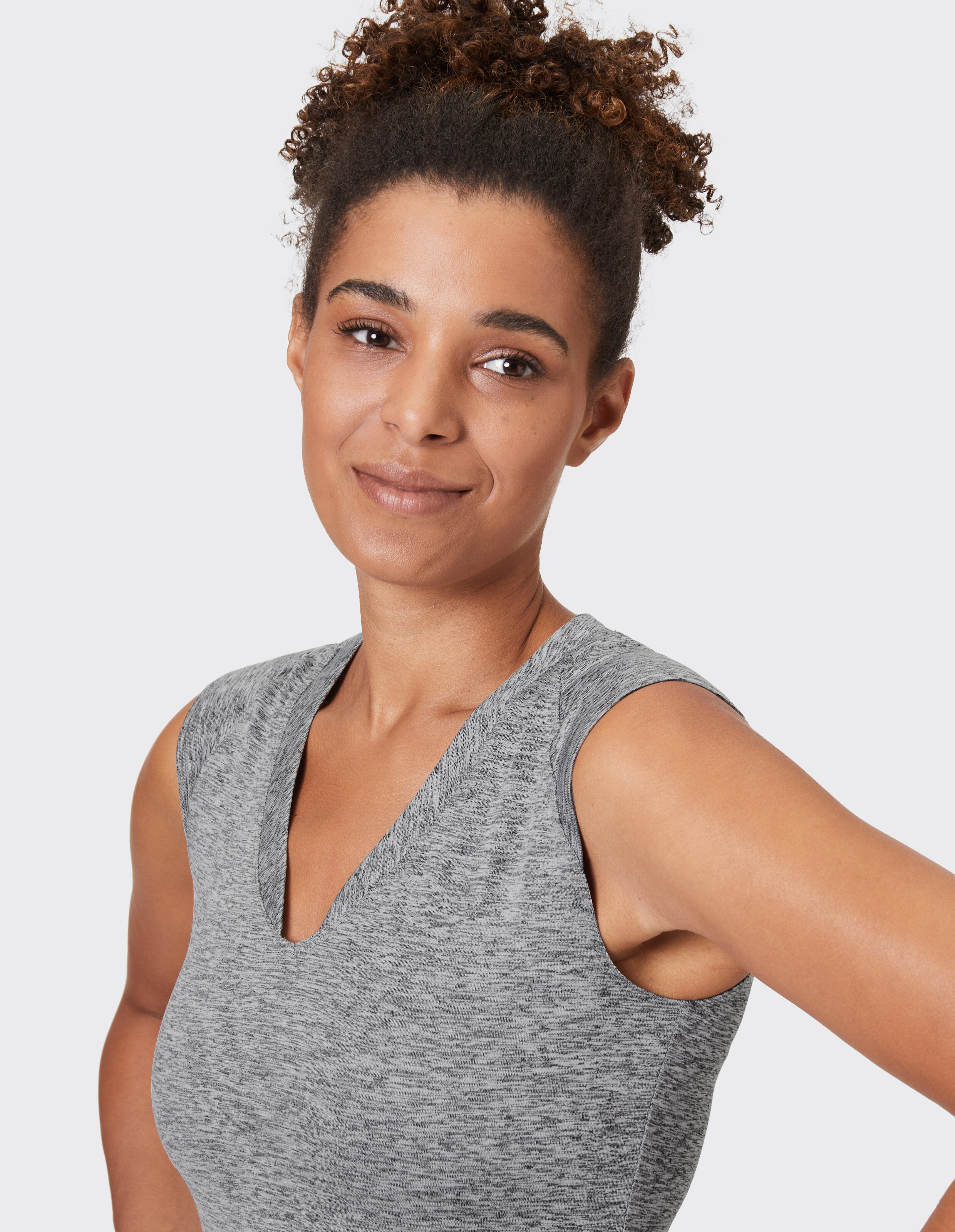 Frau trägt ein gemütliches, grau meliertes, ärmelloses Oberteil mit V-Ausschnitt für lässige Loungewear.