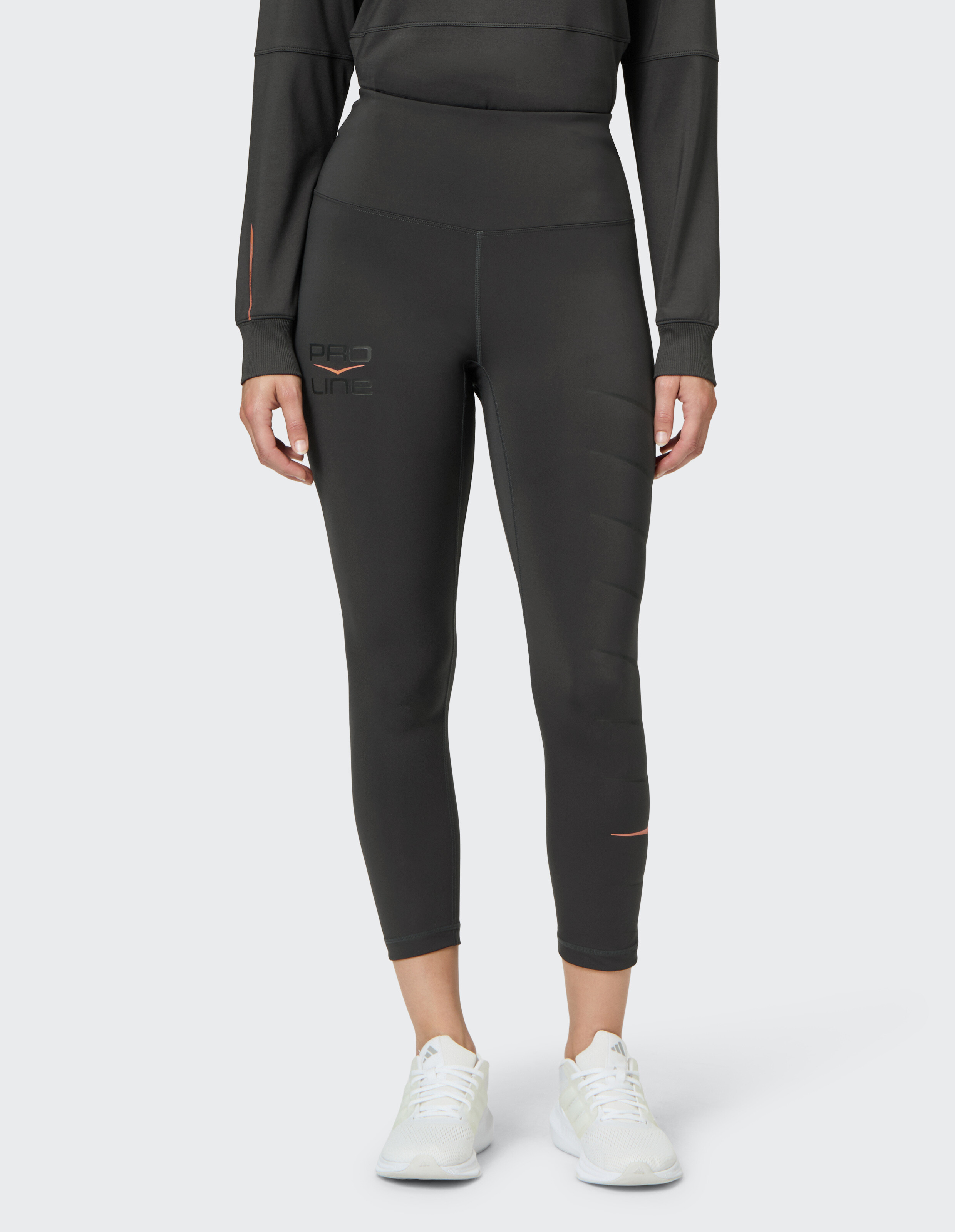 Frau trägt dunkelgraue Sportleggings mit hoher Taille und Pro Line-Branding.