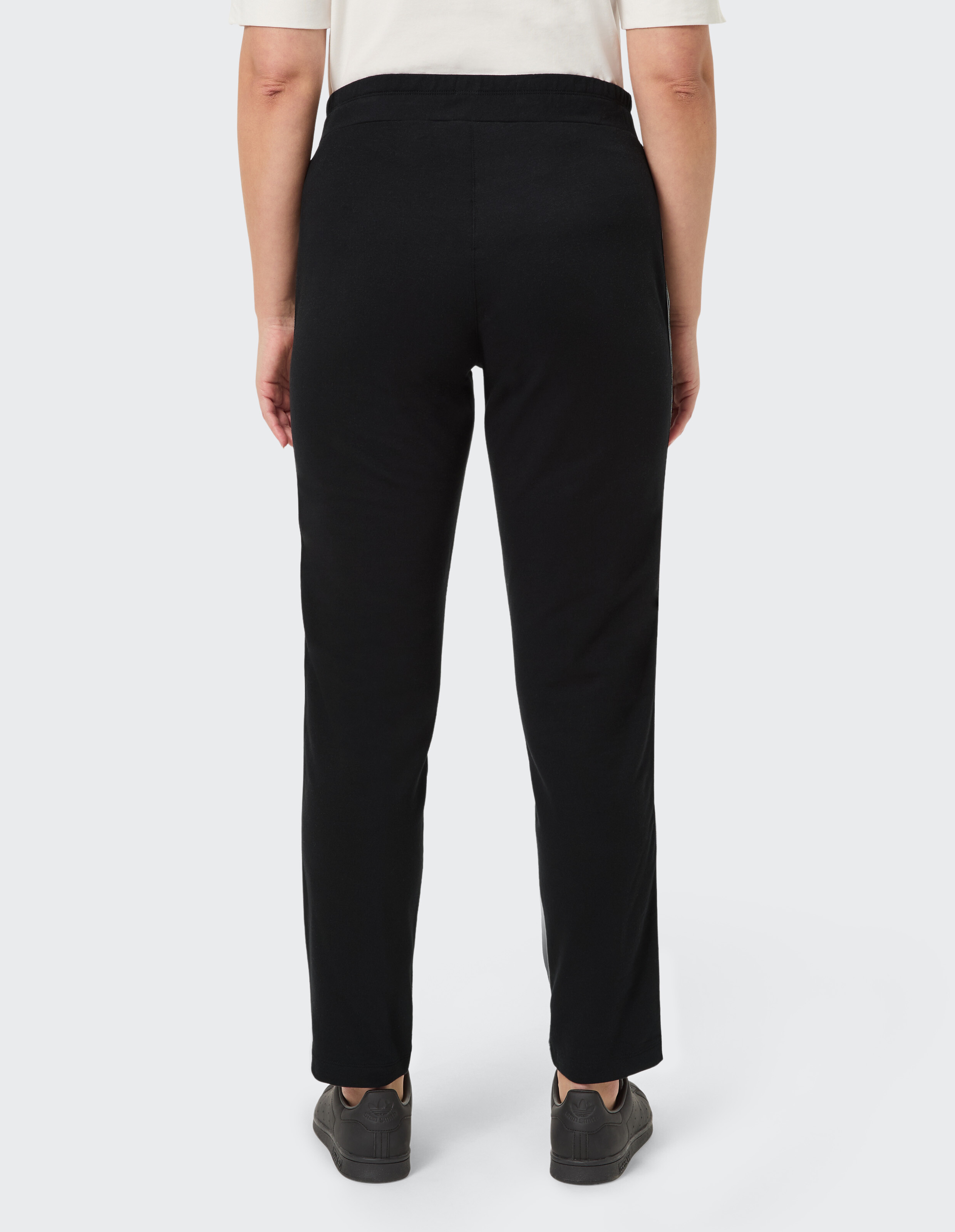 Schwarze Hose mit geradem Bein und elastischem Bund, getragen mit schwarzen Sneakers.