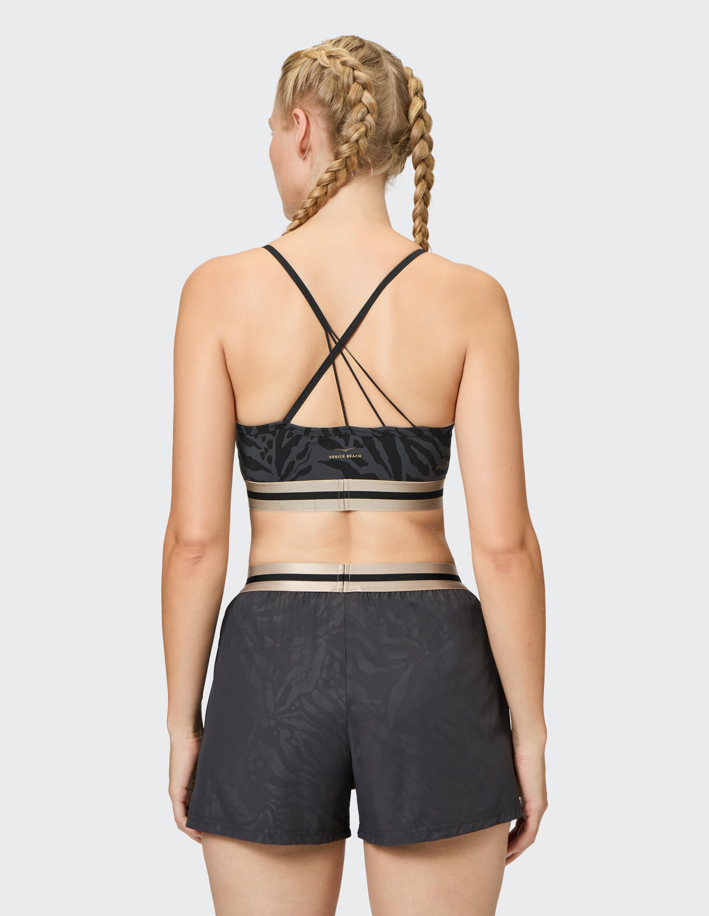 Frau trägt einen schwarzen Sport-BH mit Animal-Print und passende Shorts für lässige Aktivkleidung.