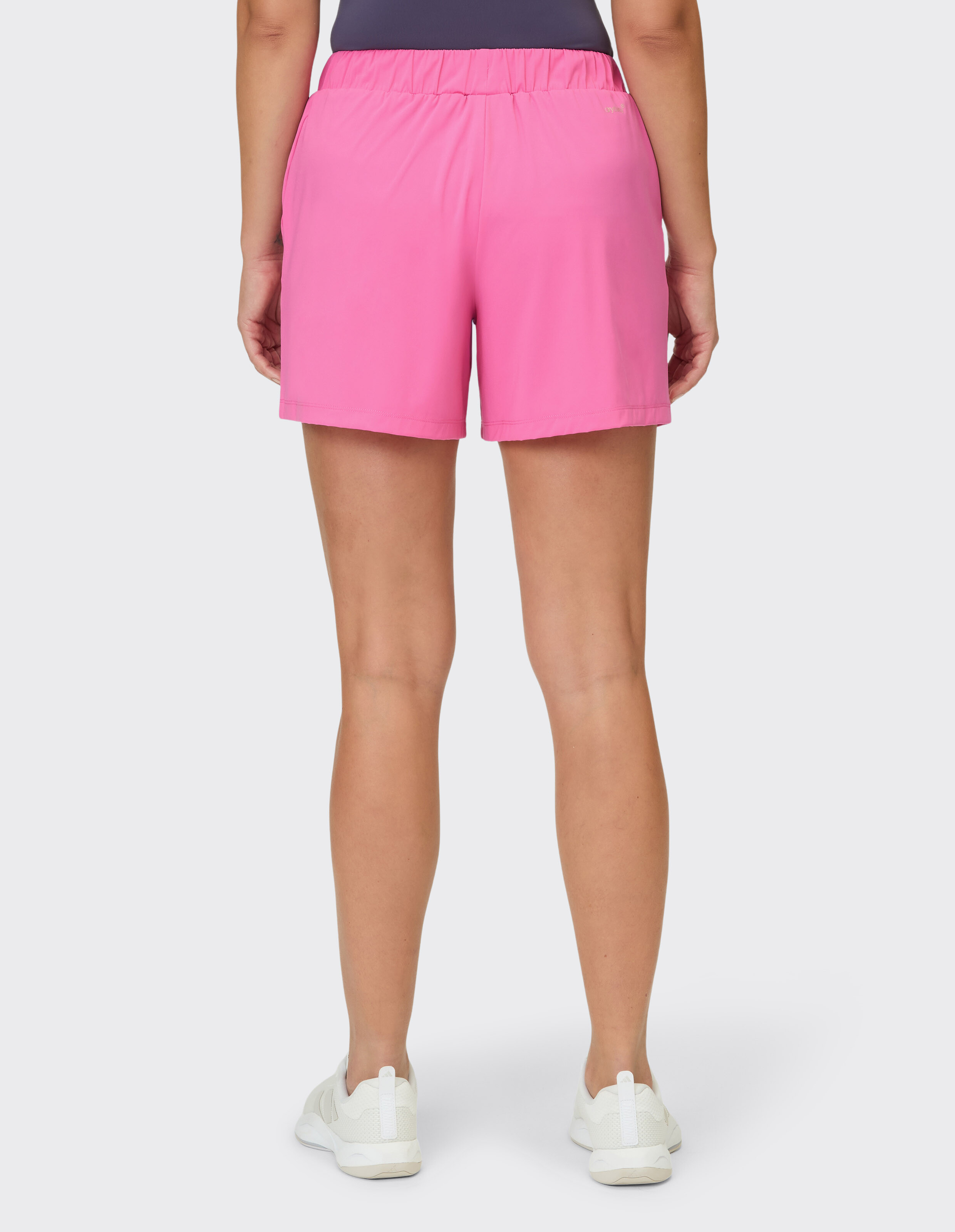 Rückansicht einer Frau in rosa Freizeitshorts und weißen Turnschuhen.