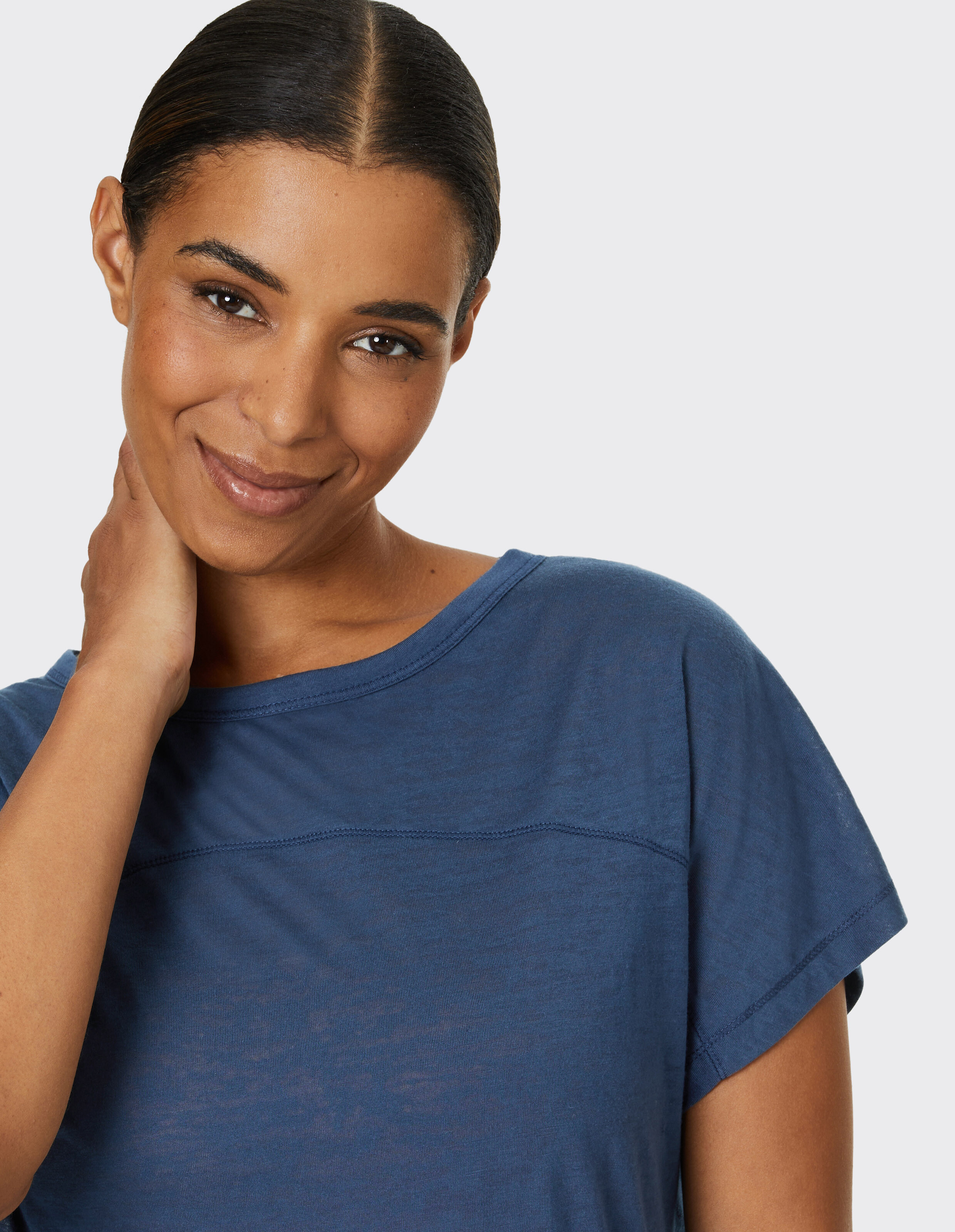 Lächelnde Frau trägt ein gemütliches blaues Freizeit-T-Shirt mit kurzen Ärmeln.