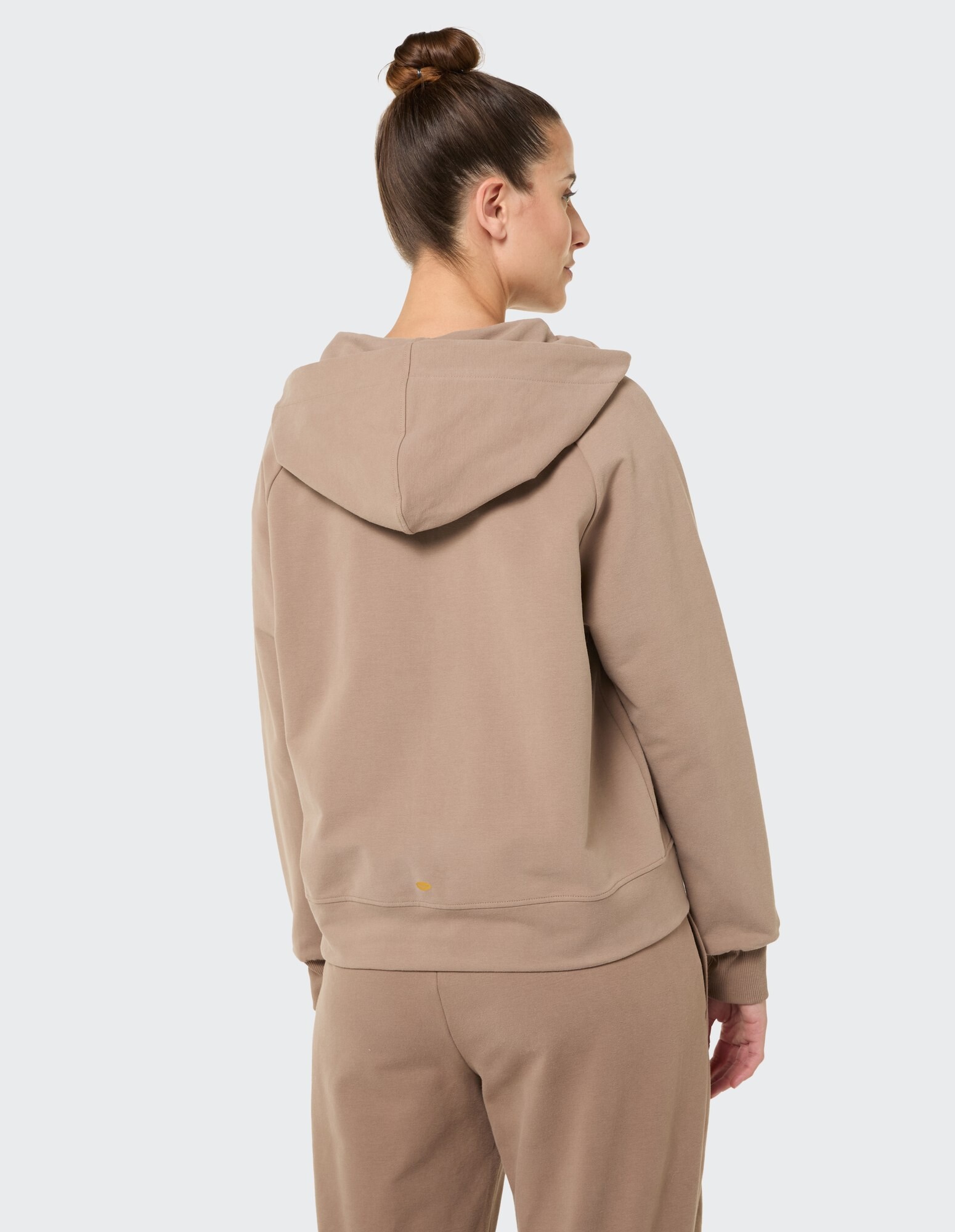 Rückansicht einer Frau in einem gemütlichen beigen Kapuzenpullover, perfekt für Freizeitkleidung.