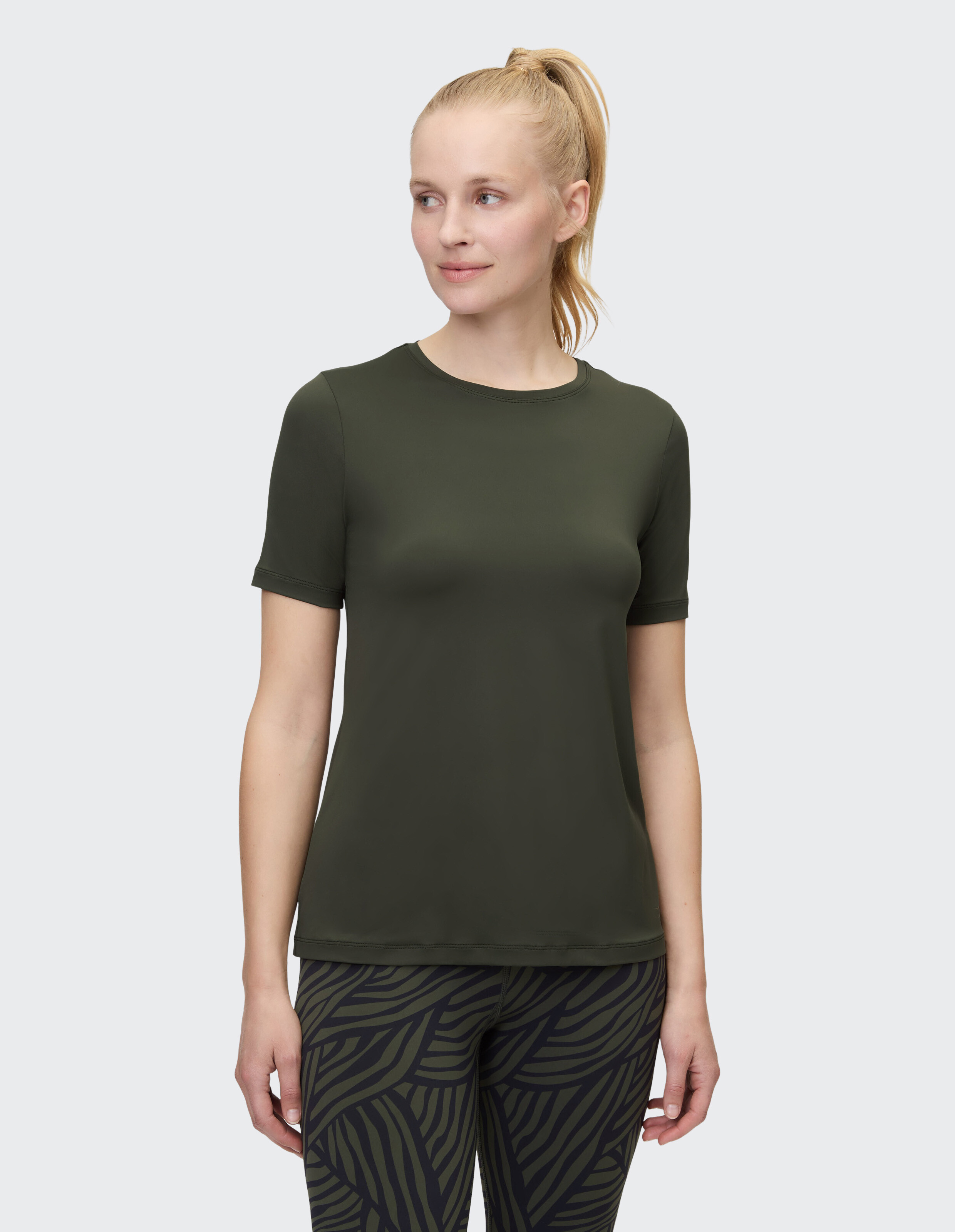 Frau trägt ein dunkelgrünes Freizeit-T-Shirt mit gemusterten Leggings für einen bequemen Look.