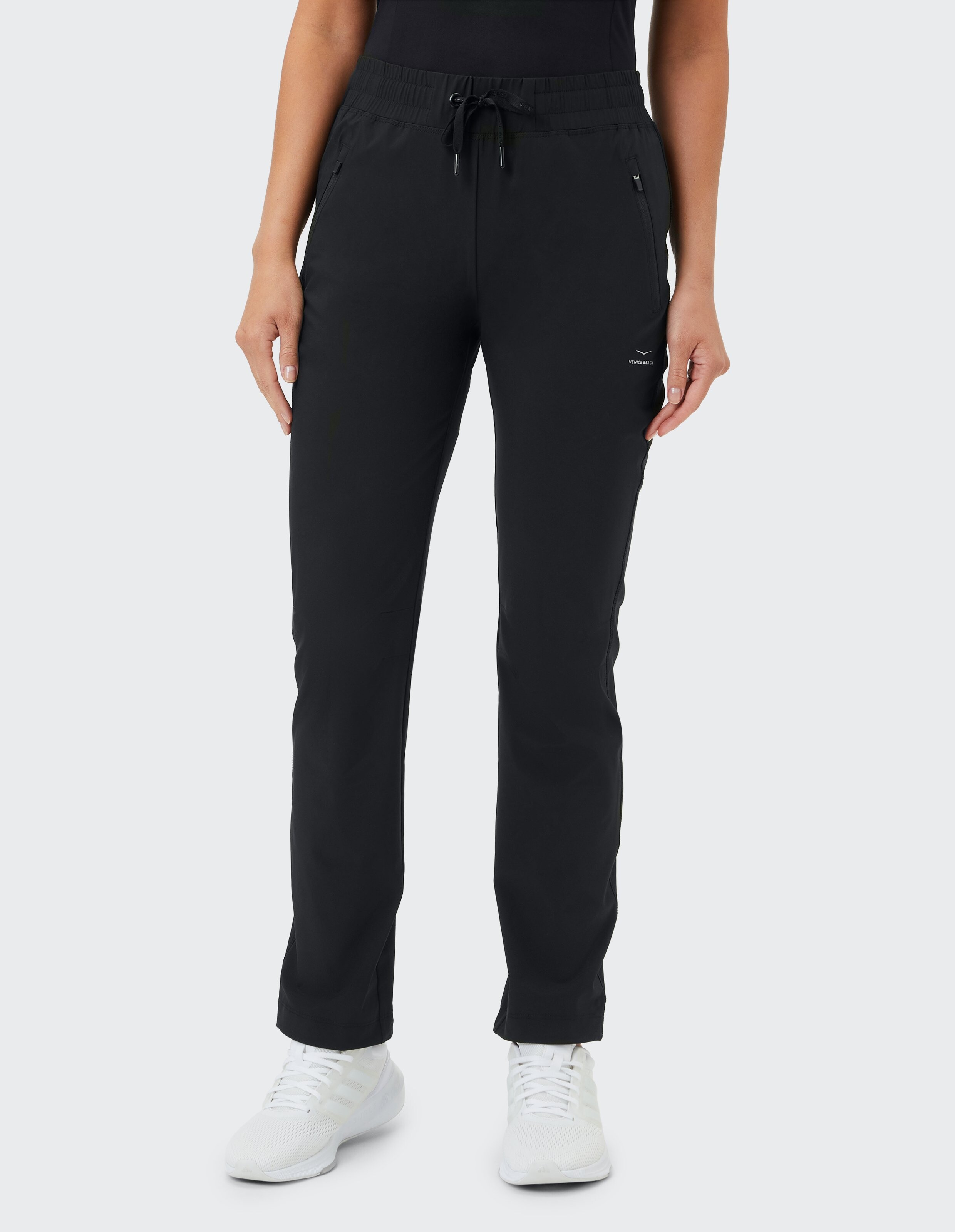 Frau trägt eine schwarze, lässige Loungehose mit Kordelzug und Seitentaschen.
