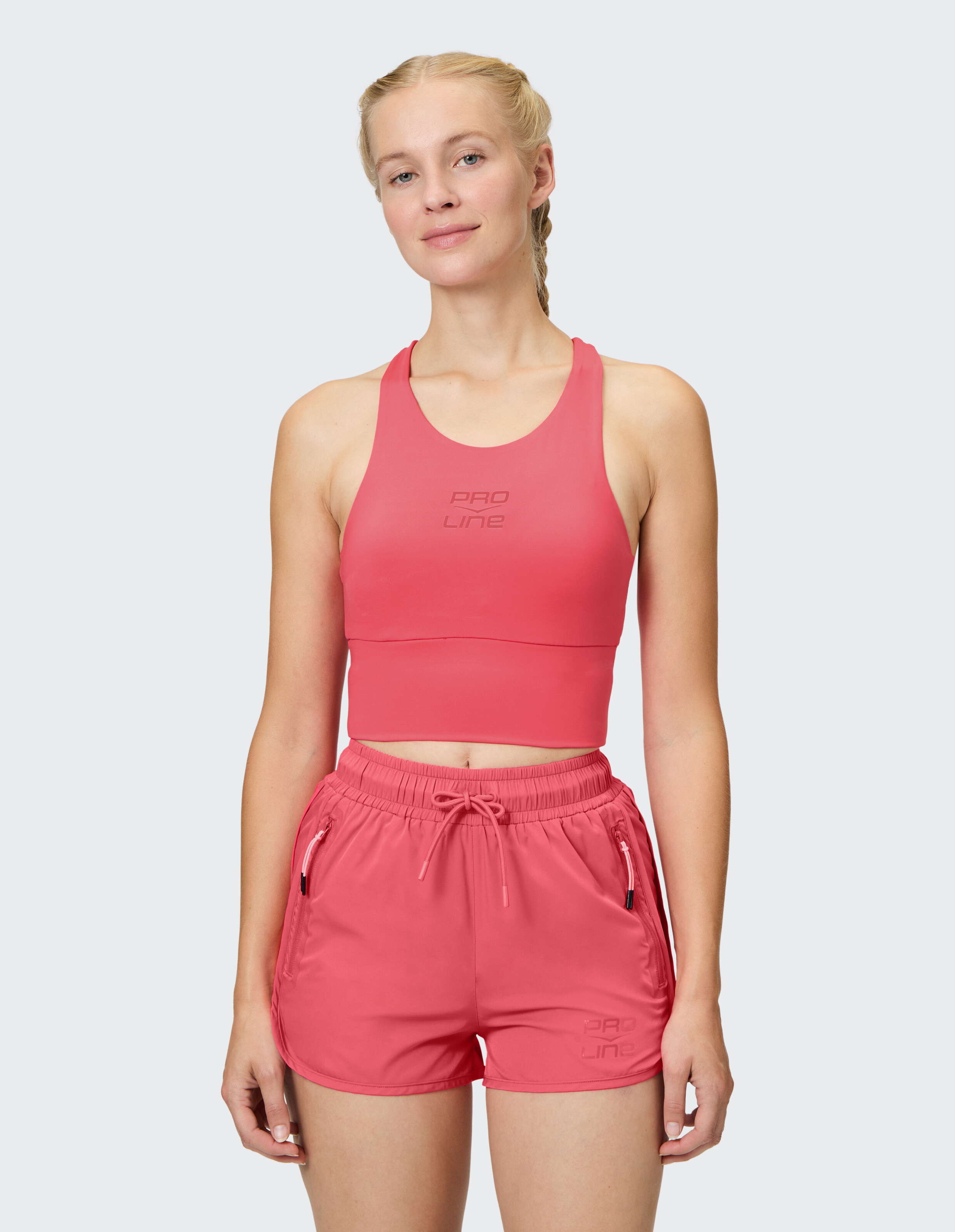 Das Model trägt einen rosa Sport-BH und passende Shorts, ideal für Aktivkleidung und Freizeitausflüge.