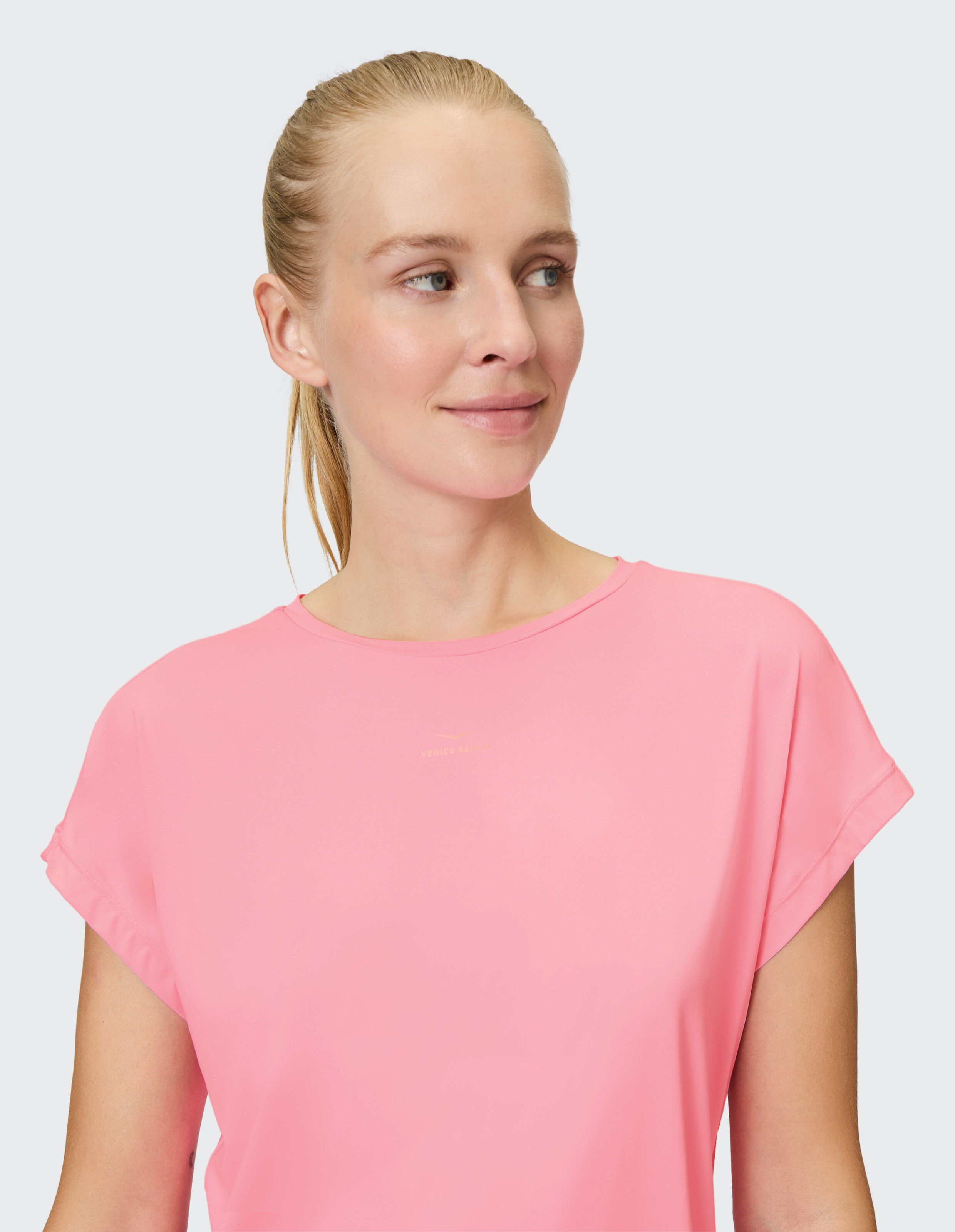 Frau trägt ein zartrosa lässiges T-Shirt mit aufgerollten Ärmeln, perfekt für entspannte Ausflüge.