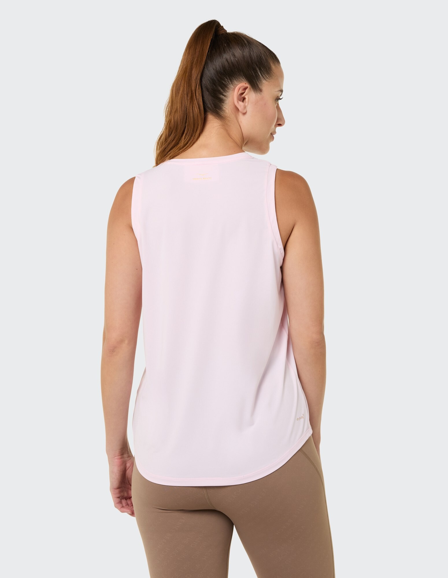Rückansicht einer Frau in einem hellrosa ärmellosen Top und braunen Leggings.