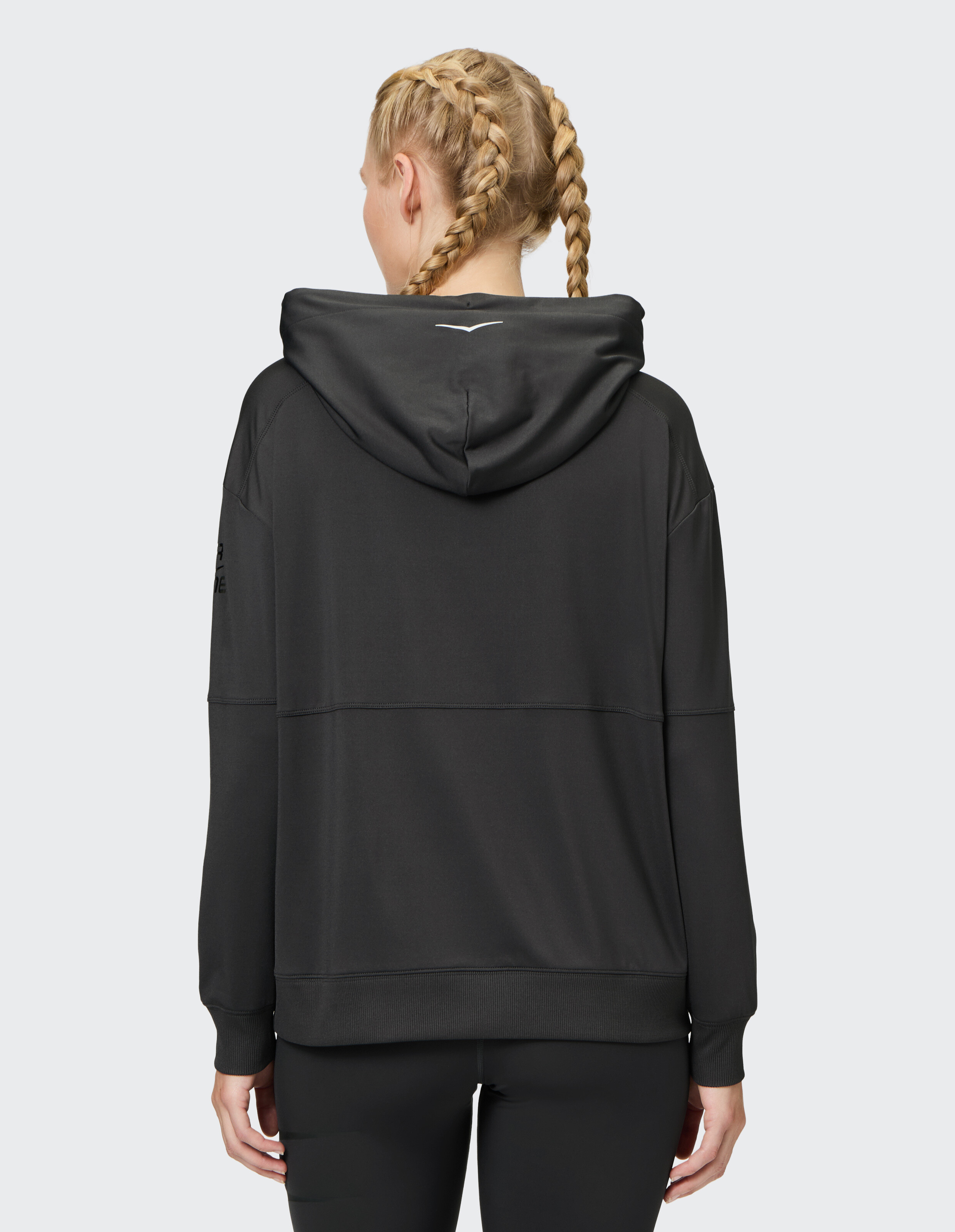 Frau trägt einen kuscheligen schwarzen ELBSAND-Hoodie mit Kapuze, Rückansicht, lässiger Loungewear-Stil.