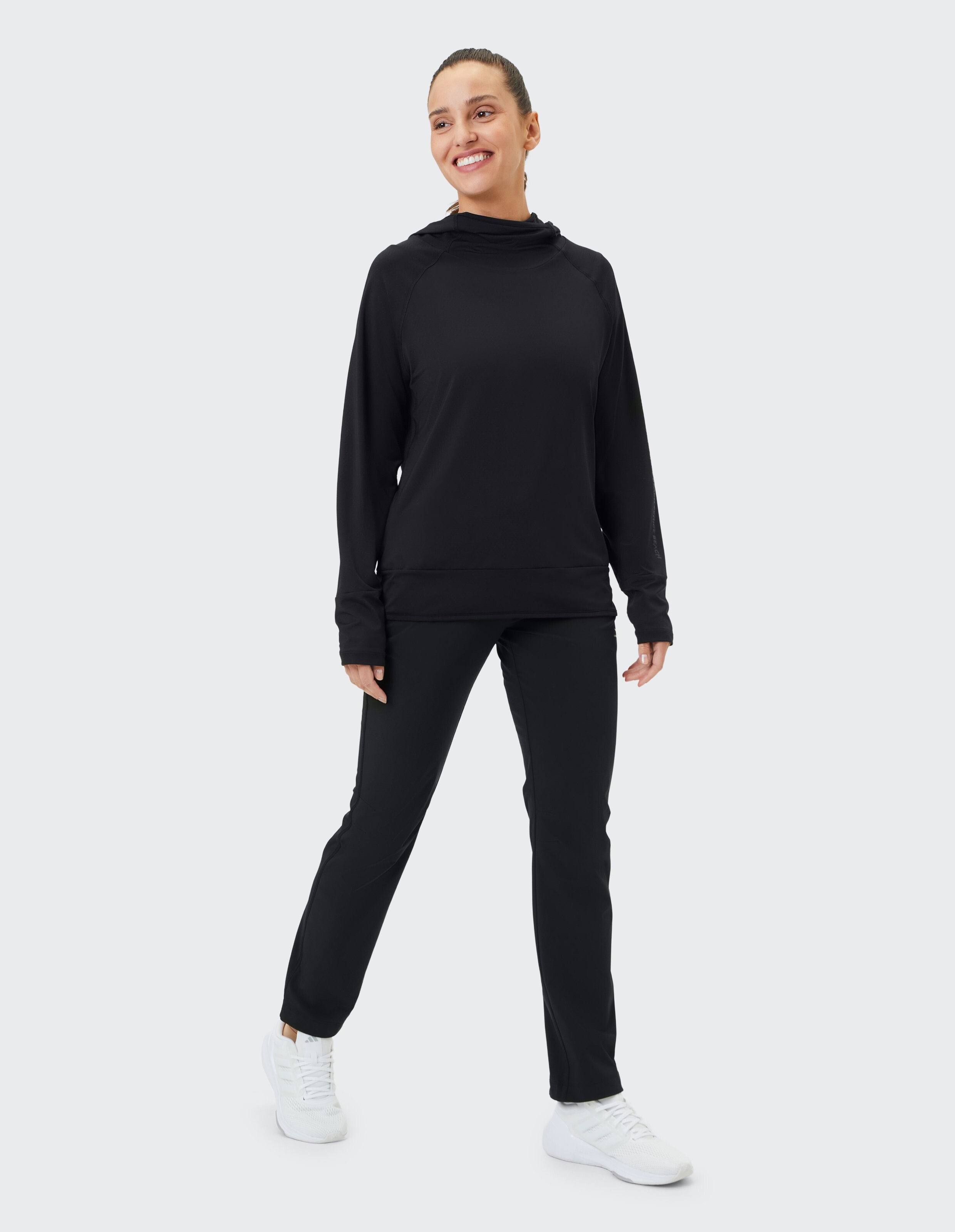 Frau in schwarzem, lässigem Kapuzenpullover und Hose, perfekt zum Faulenzen oder für Freizeitausflüge.
