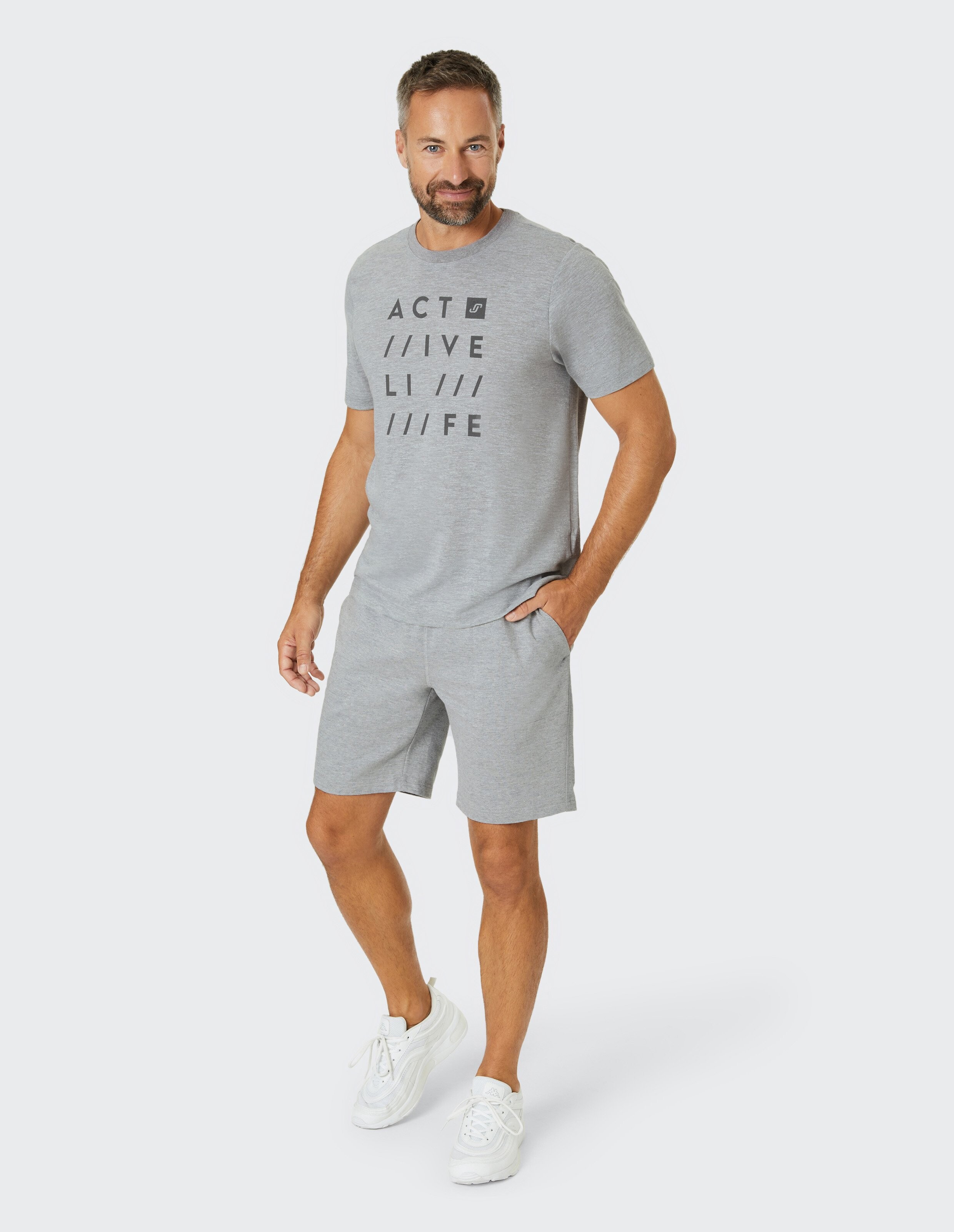 Mann trägt ein graues ELBSAND-Freizeit-T-Shirt und passende Shorts für einen bequemen Lounge-Look.