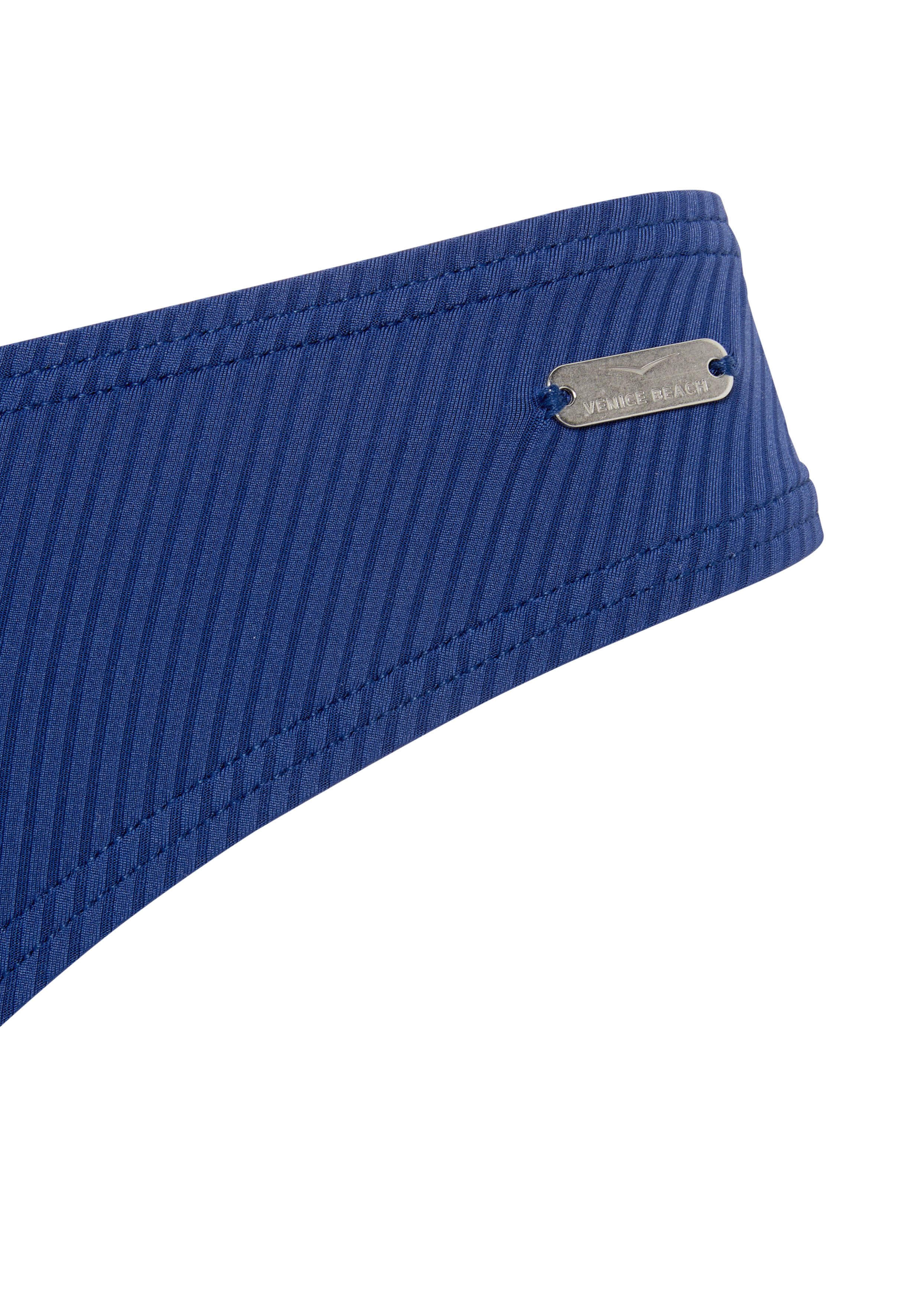 Nahaufnahme einer blauen, gerippten Bikinihose mit einem Venice Beach-Logoetikett aus Metall.