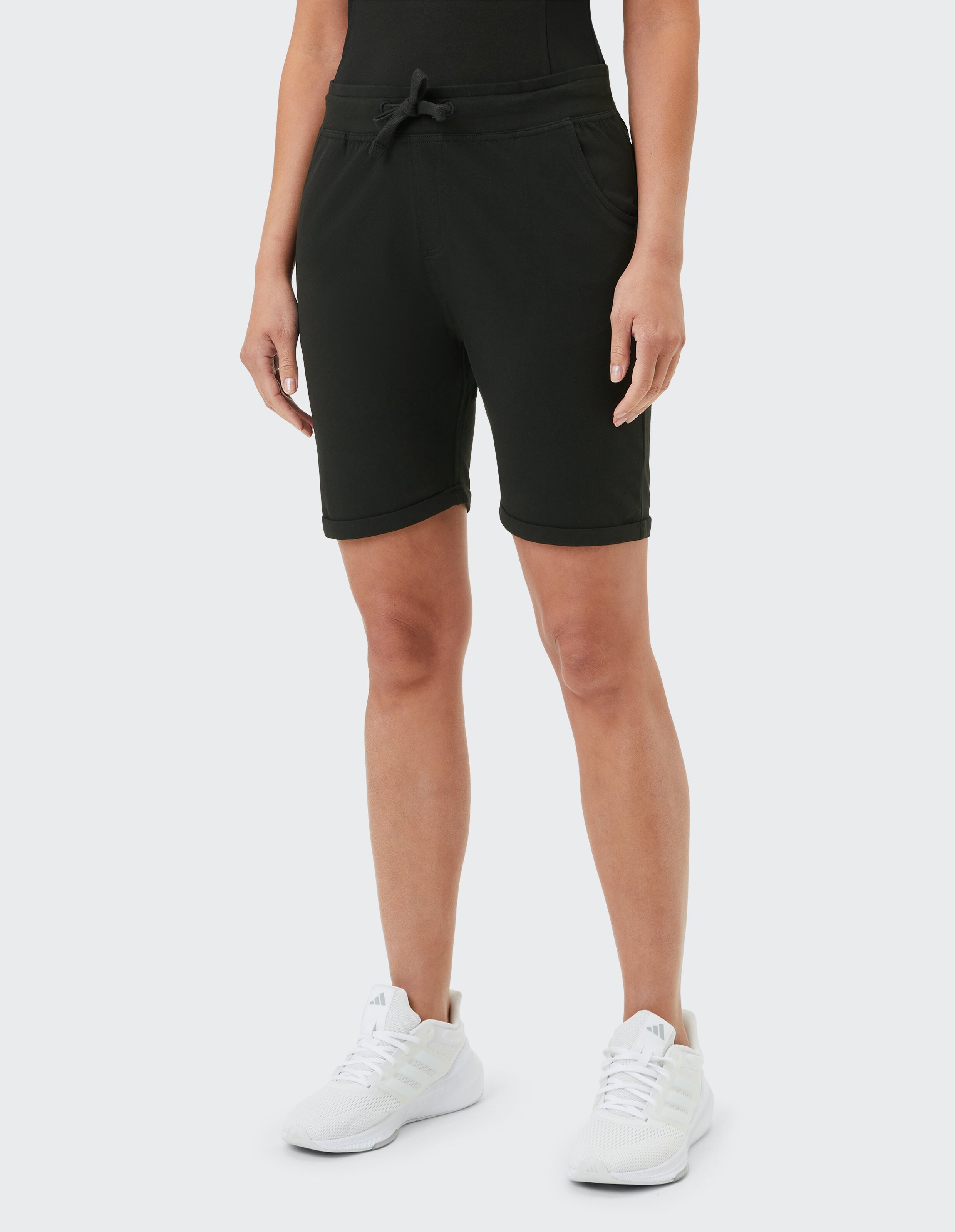 Frau trägt schwarze, lässige Jersey-Shorts mit Kordelzug in der Taille zum Entspannen.