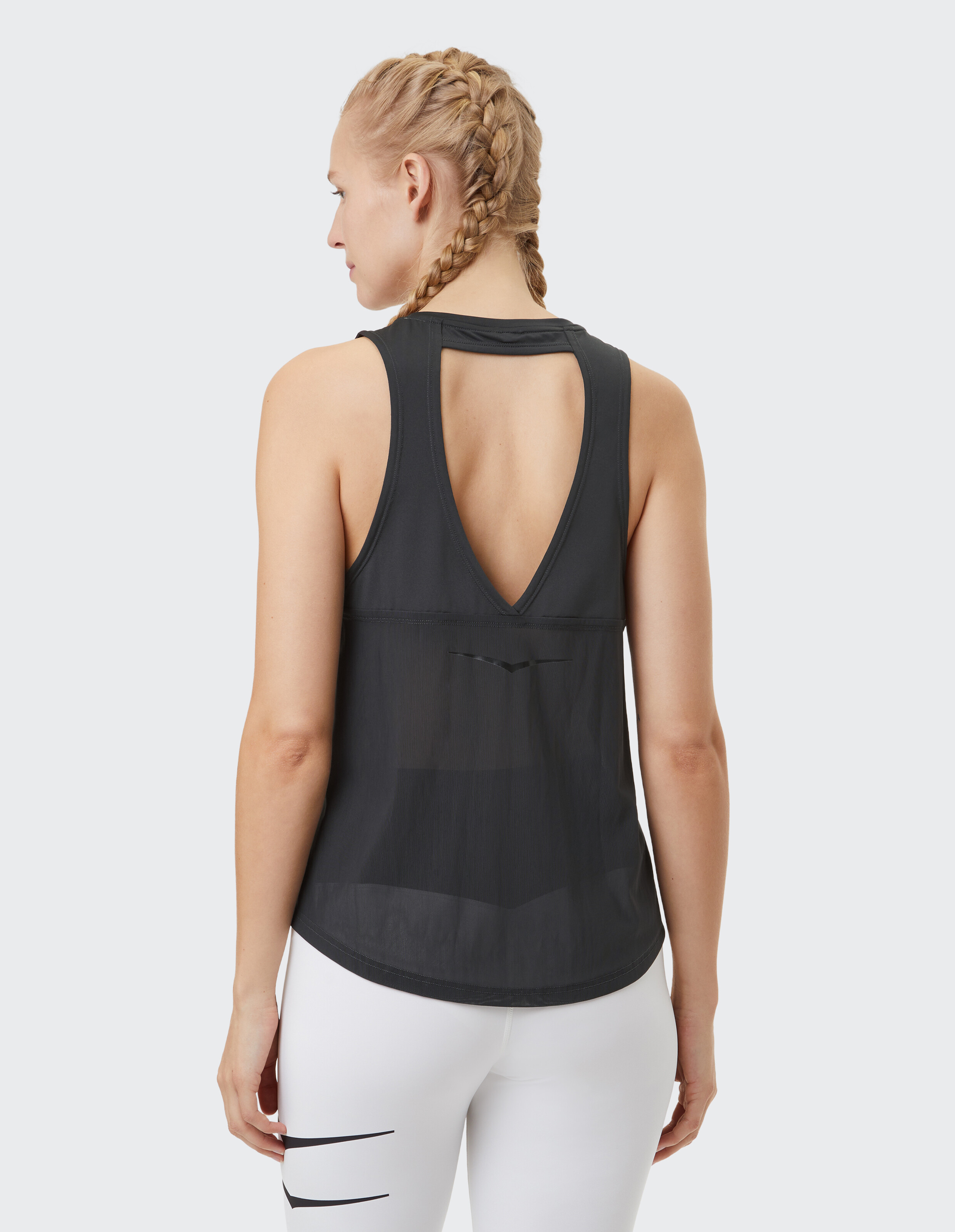 Frau trägt ein schwarzes ärmelloses Tanktop mit ausgeschnittenem Rückendetail.