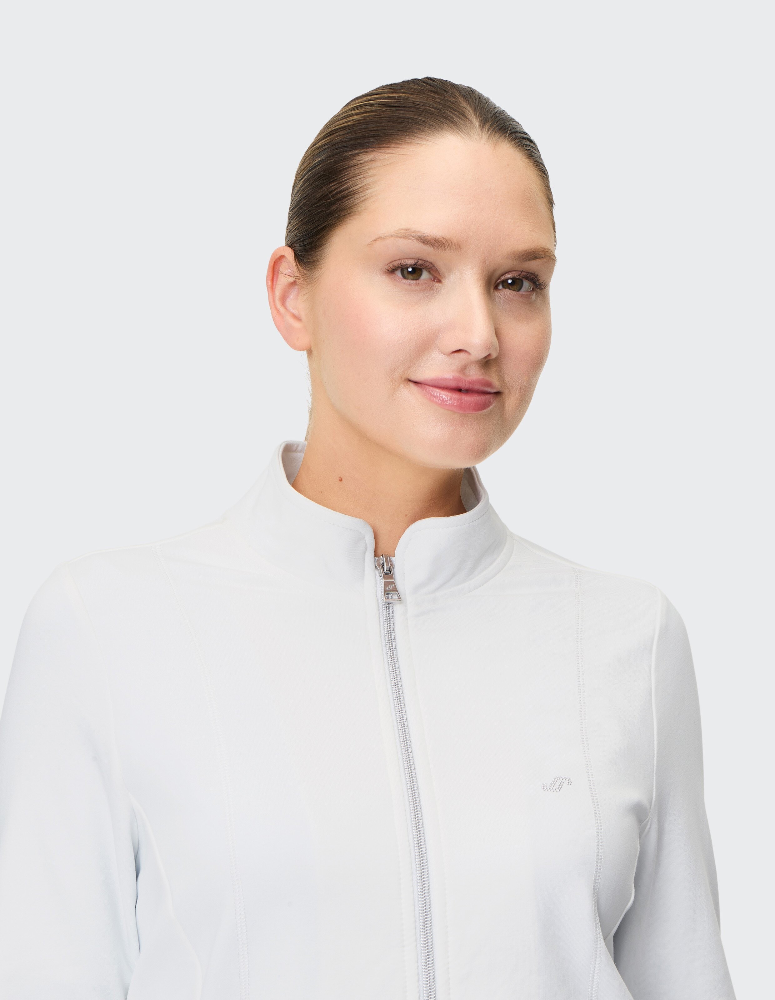 Frau trägt eine weiße Freizeitjacke mit Reißverschluss und Stehkragen, perfekt für gemütliche Lounge-Kleidung.