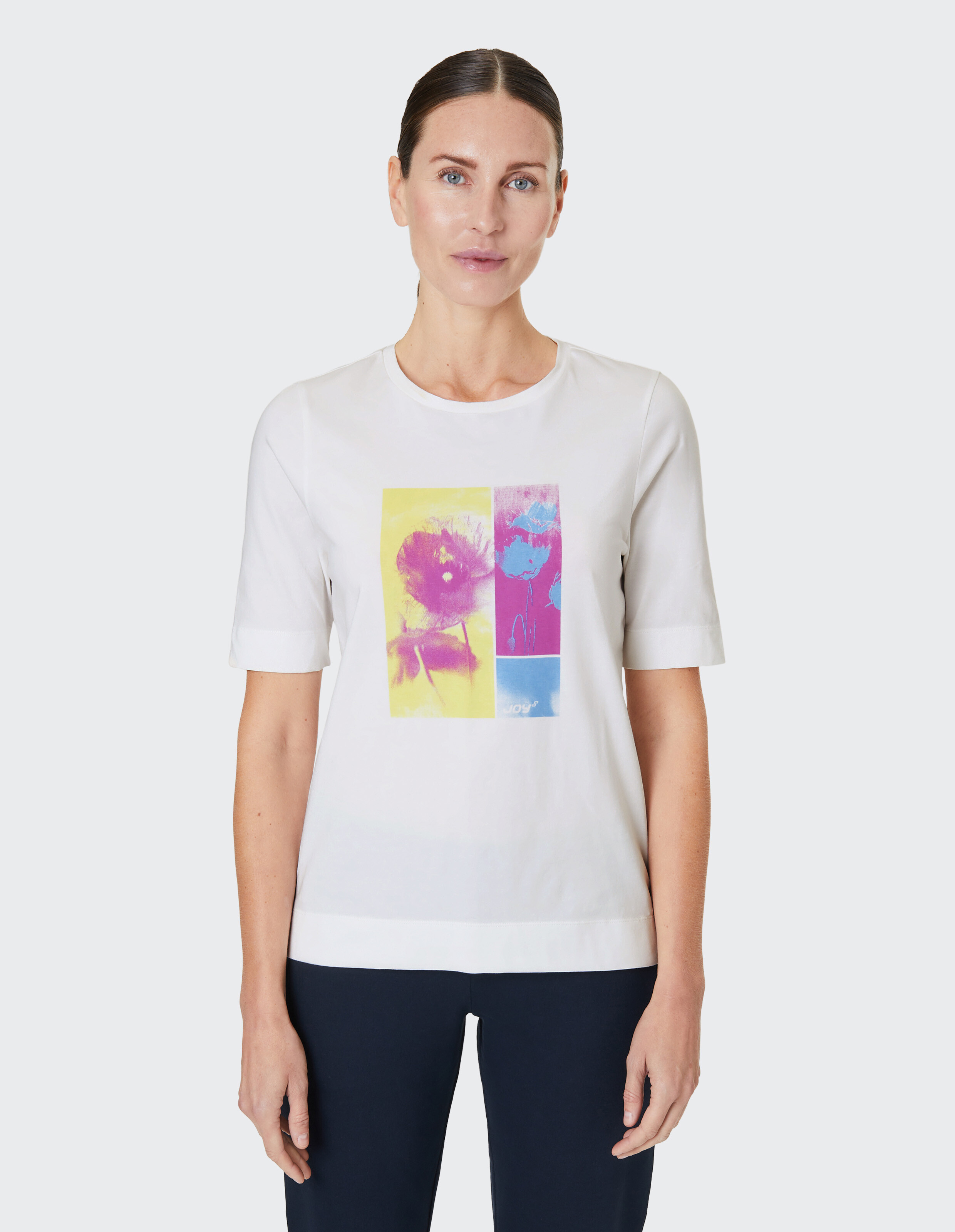 Weißes T-Shirt mit buntem Blumenprint in gelben und violetten Tönen auf der Vorderseite, das ein künstlerisches Design zeigt.