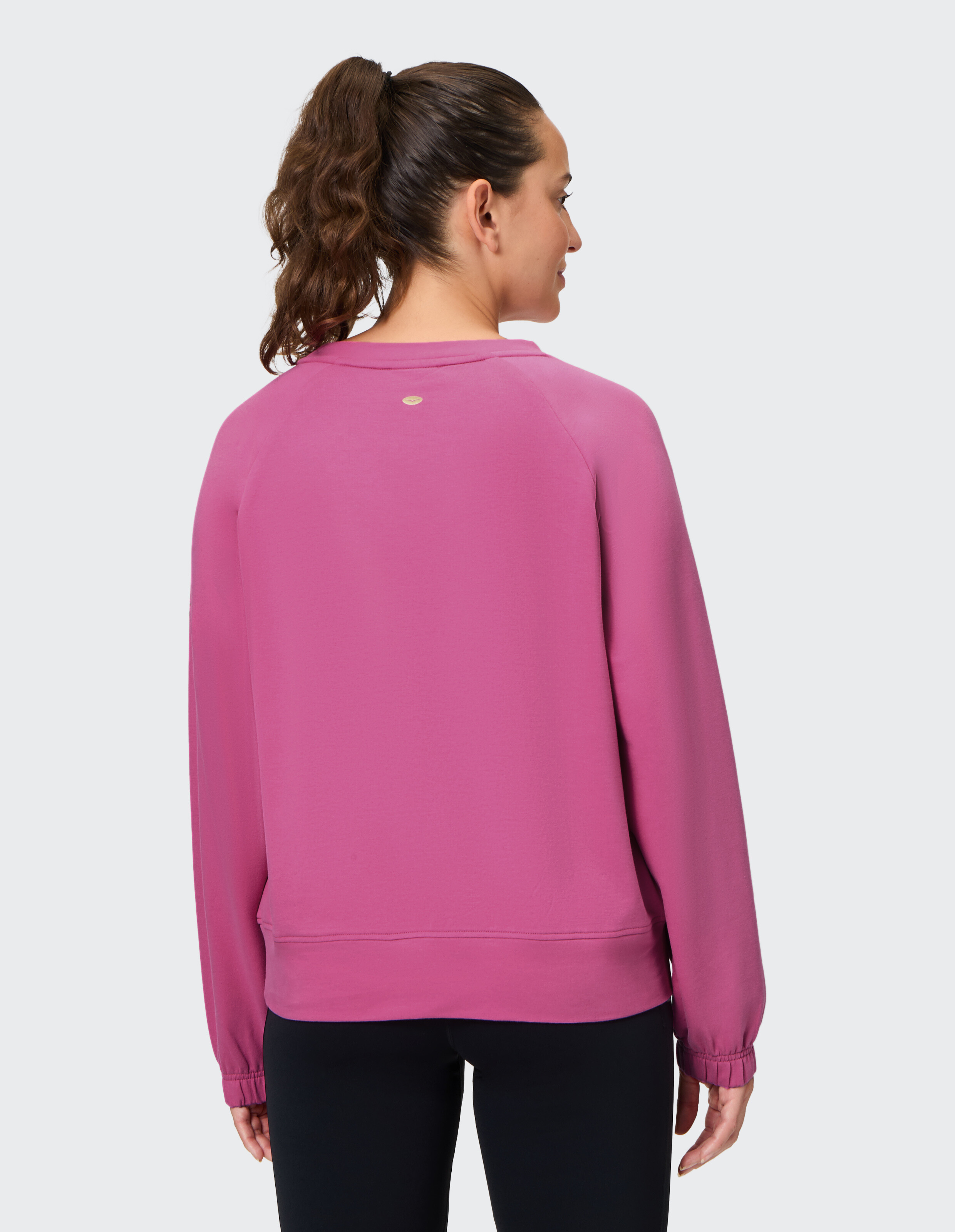 Rückansicht einer Frau in einem rosa lässigen Sweatshirt, perfekt zum Entspannen.