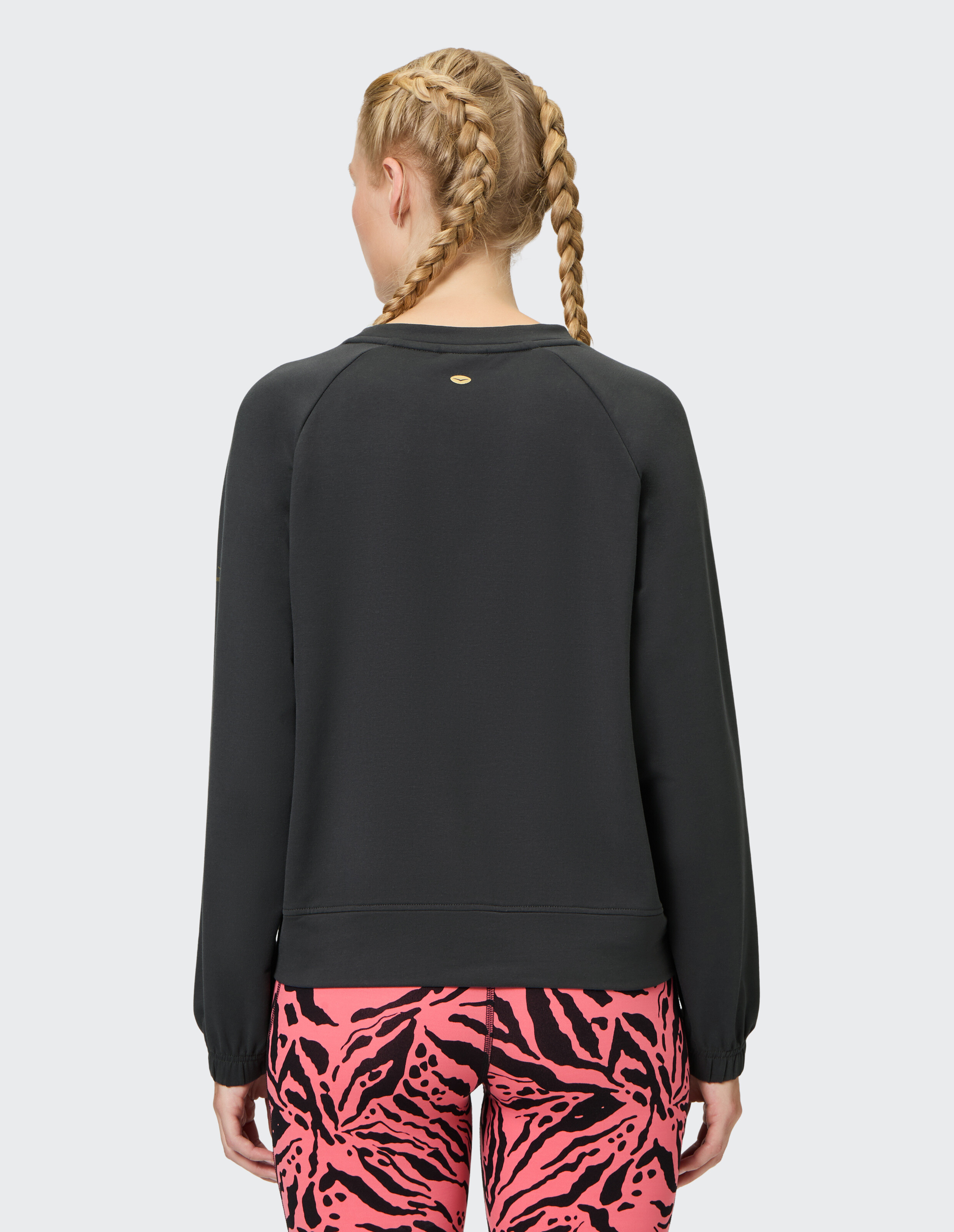 Rückansicht des Venice Beach Sweatshirt Eartha in Schwarz, gepaart mit rosa Leggings mit Animal-Print.