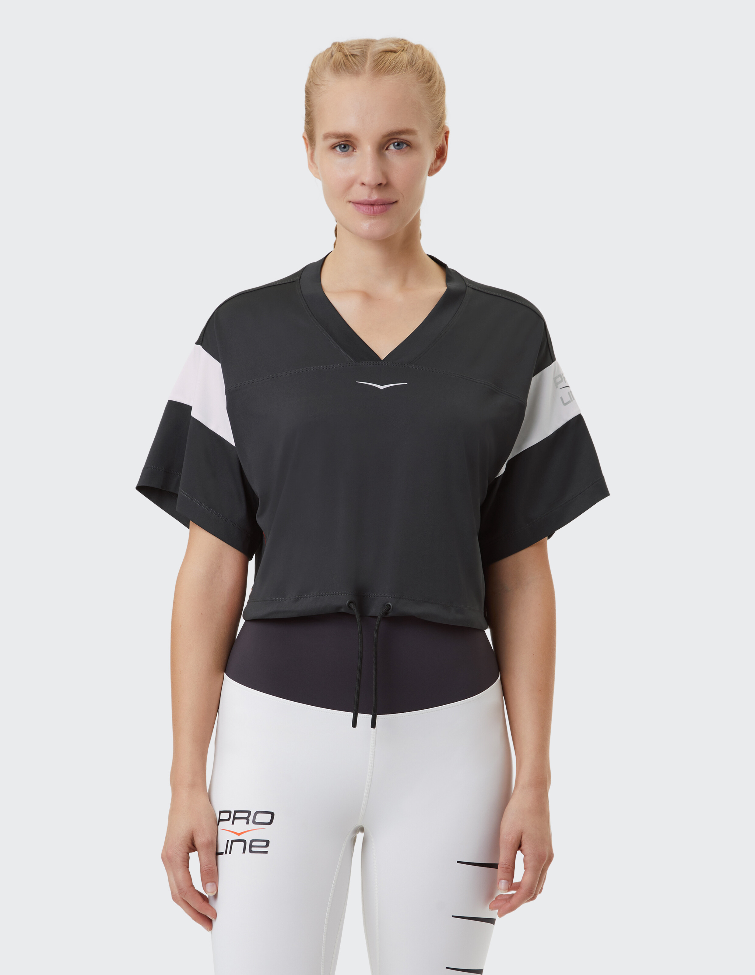 Frau trägt ein schwarzes, kurzes Sportshirt mit V-Ausschnitt und weißen Ärmelakzenten.