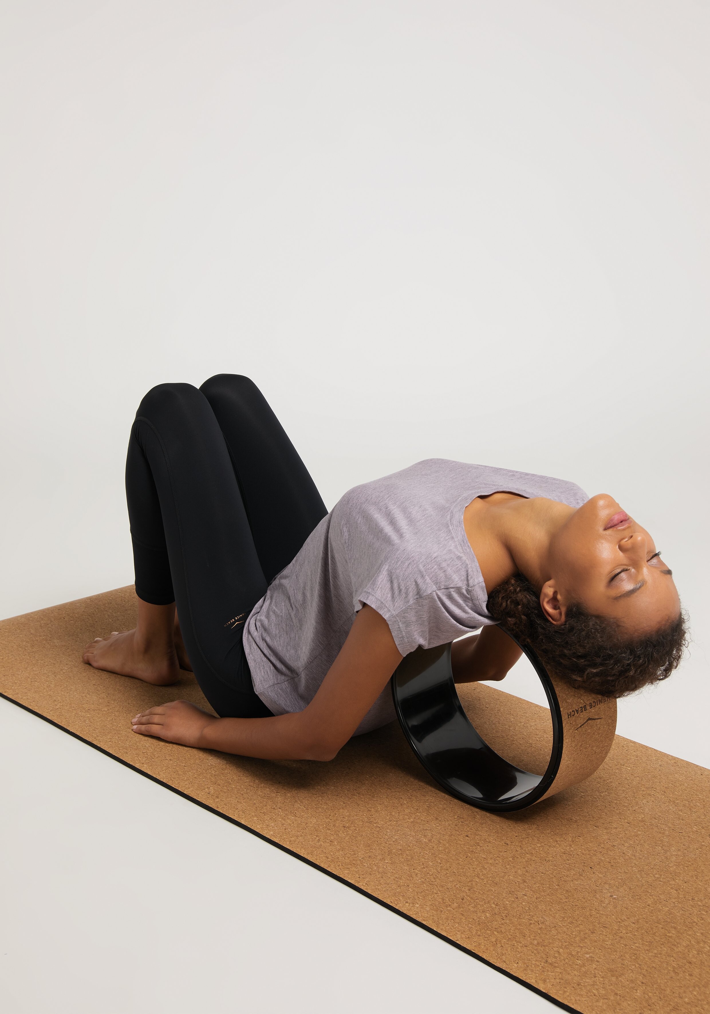 Frau nutzt ein Cork-Yoga-Rad von Venice Beach zur Rückendehnung auf einer Matte.