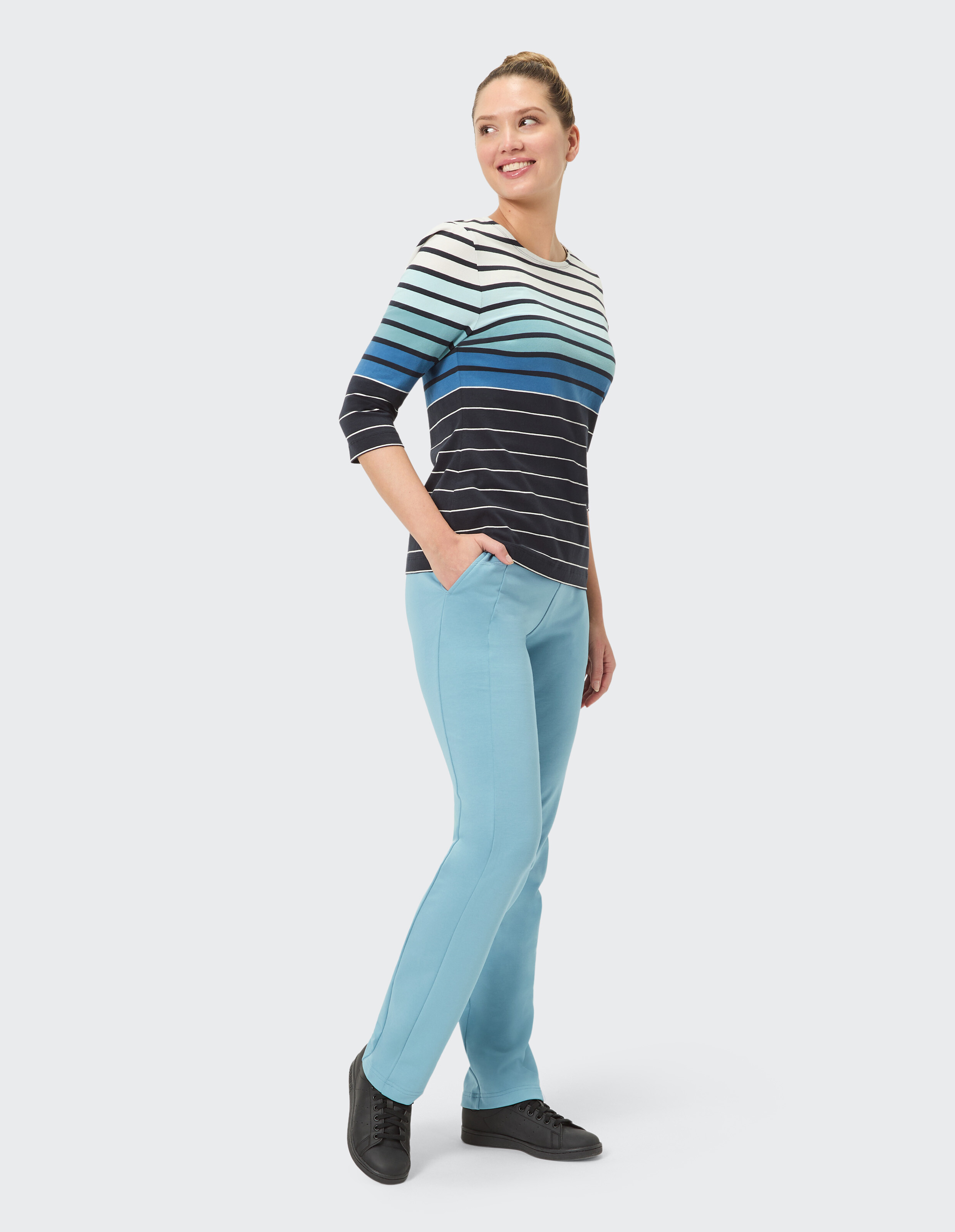 Frau in gestreiftem blau-weißem Oberteil mit hellblauer Hose, stilvolle Freizeitkleidung.