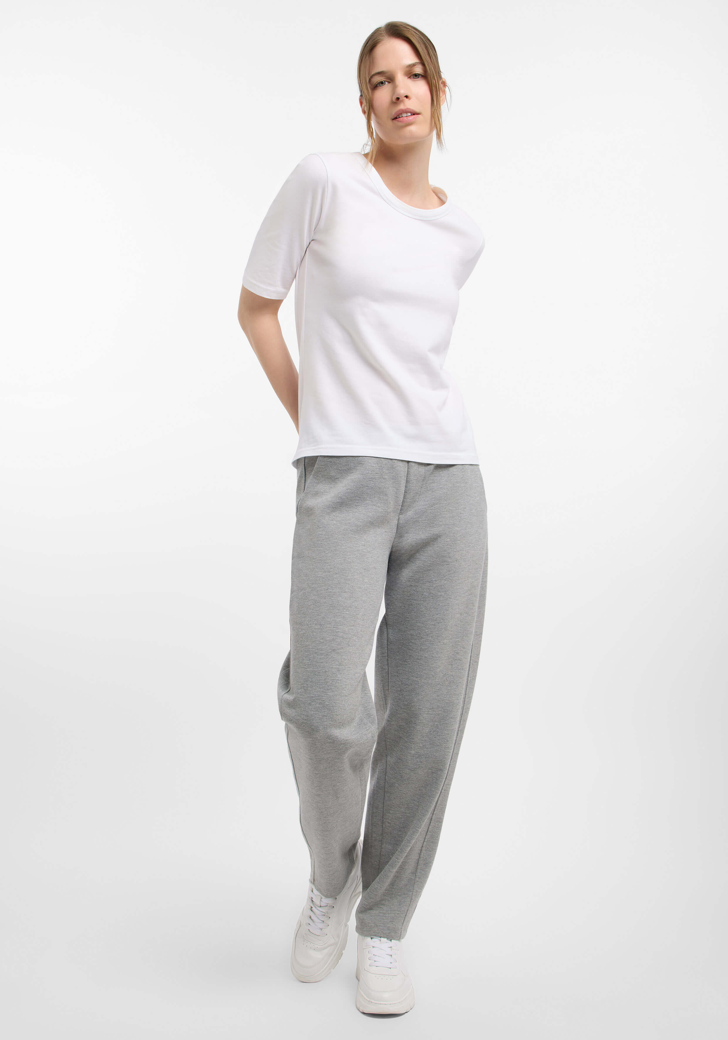 Frau trägt ein weißes T-Shirt und eine graue Jogginghose für einen gemütlichen, lässigen Look.