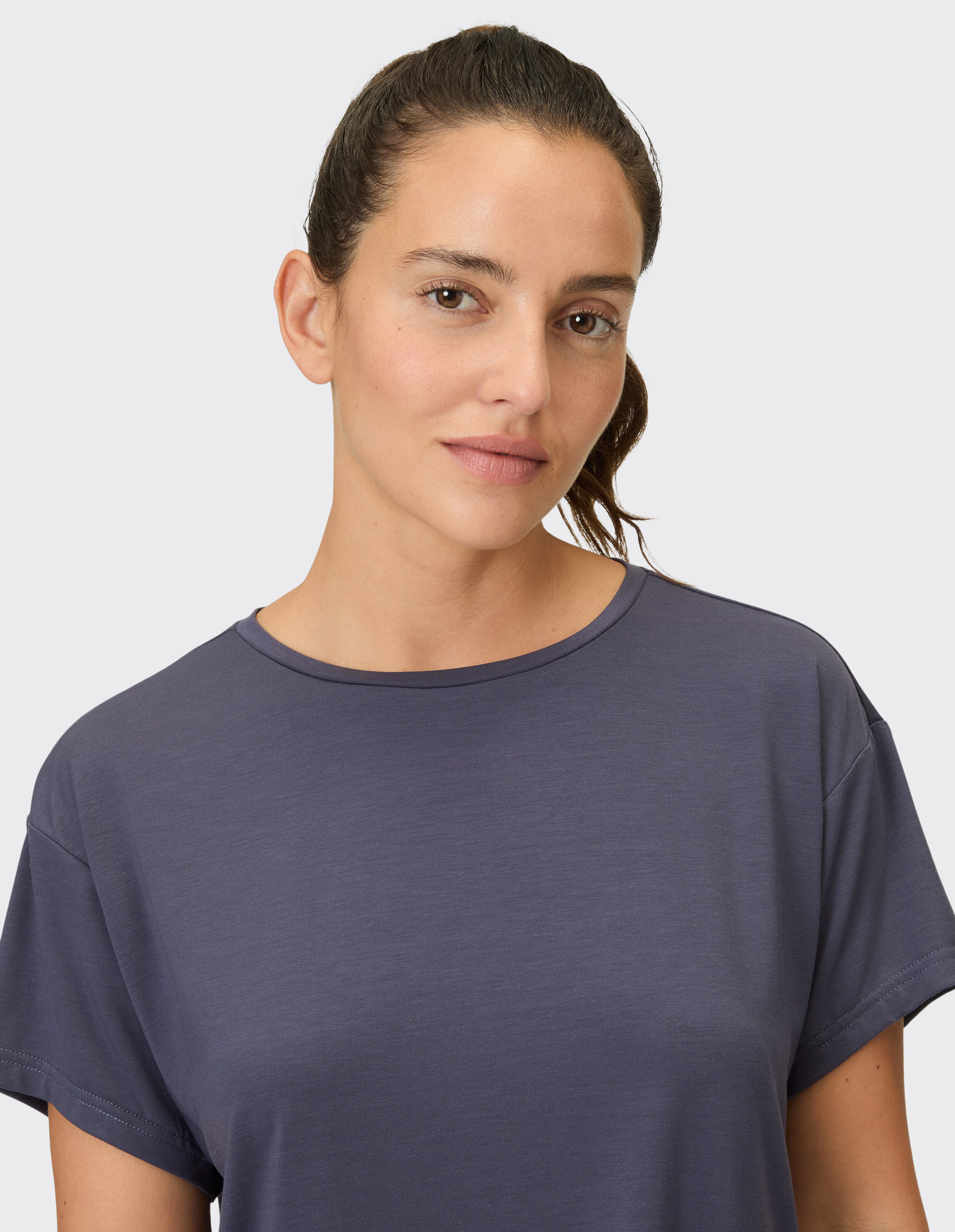 Nahaufnahme einer Frau, die ein gemütliches dunkelviolettes Freizeit-T-Shirt trägt.