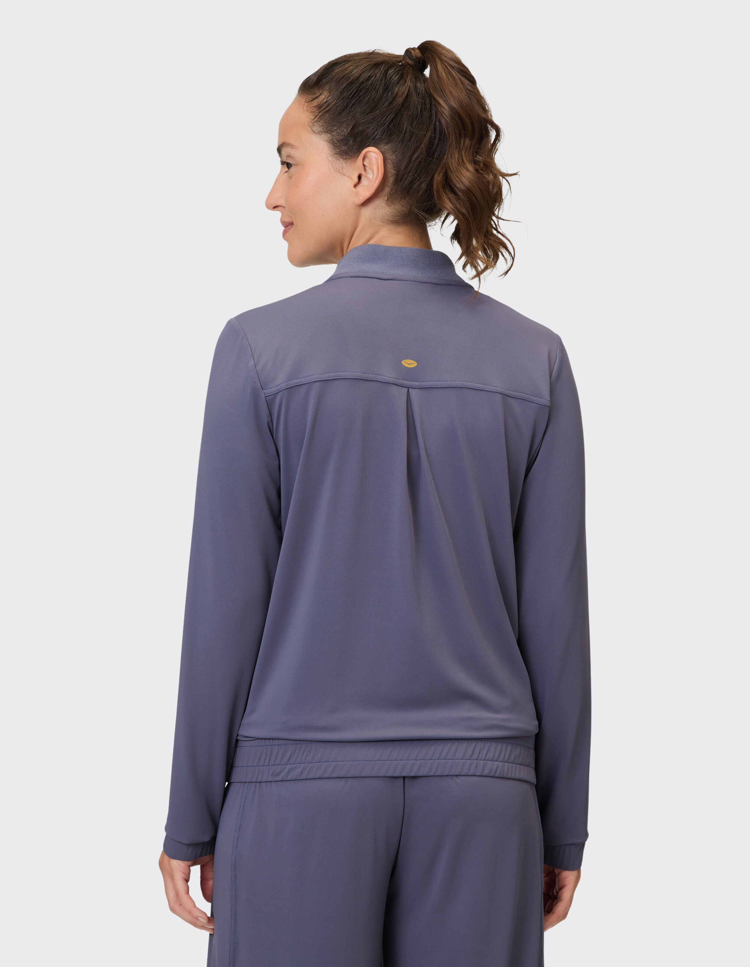 Rückansicht einer Frau in einem gemütlichen lila Langarm-Top, perfekt für Freizeitkleidung.