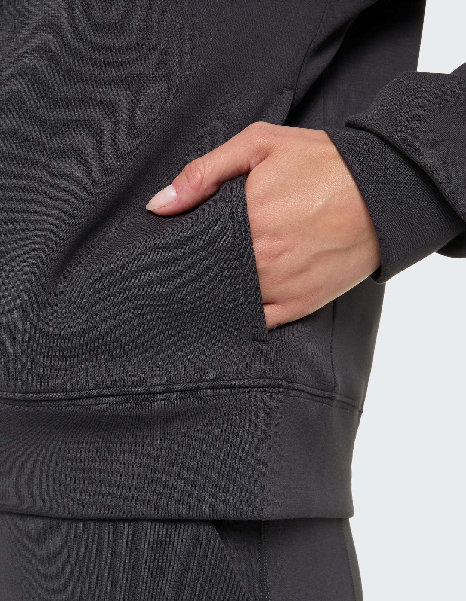 Nahaufnahme einer Hand in der Tasche eines dunkelgrauen Freizeit-Sweatshirts.