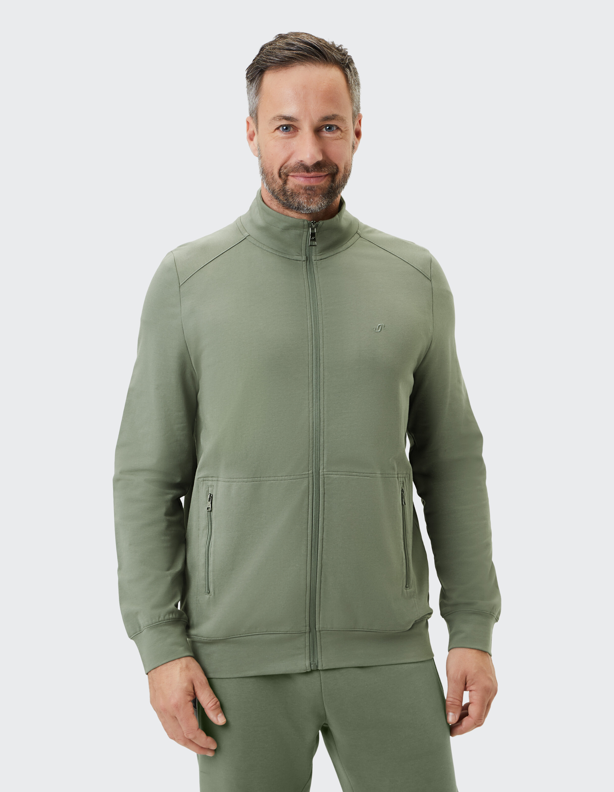 Grüne Unisex-Freizeitjacke mit durchgehendem Reißverschluss, zwei Reißverschlusstaschen und hohem Kragen aus leichtem Material.