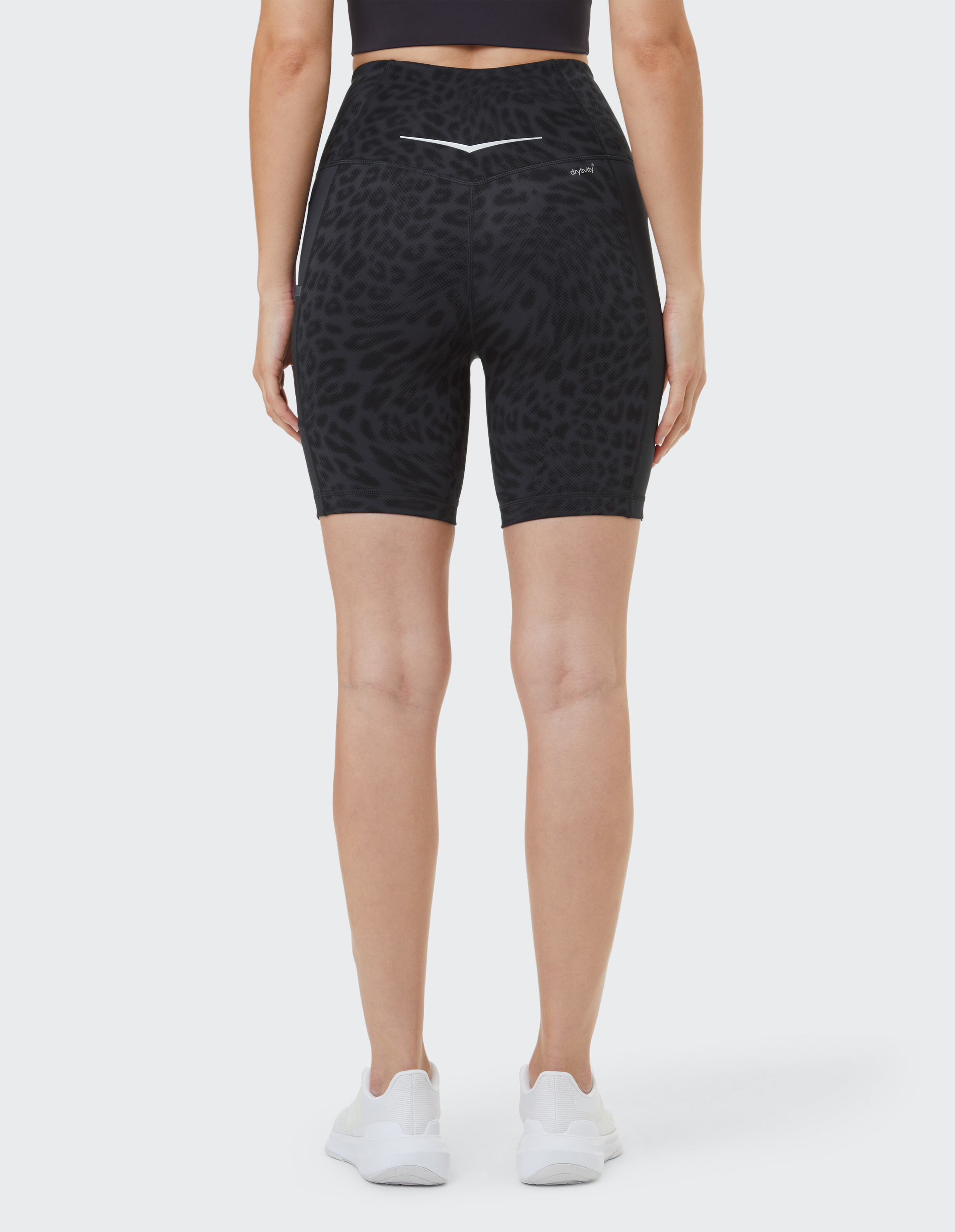 Rückansicht einer Frau in hoch taillierten schwarzen Shorts mit Animal-Print, gepaart mit weißen Turnschuhen.