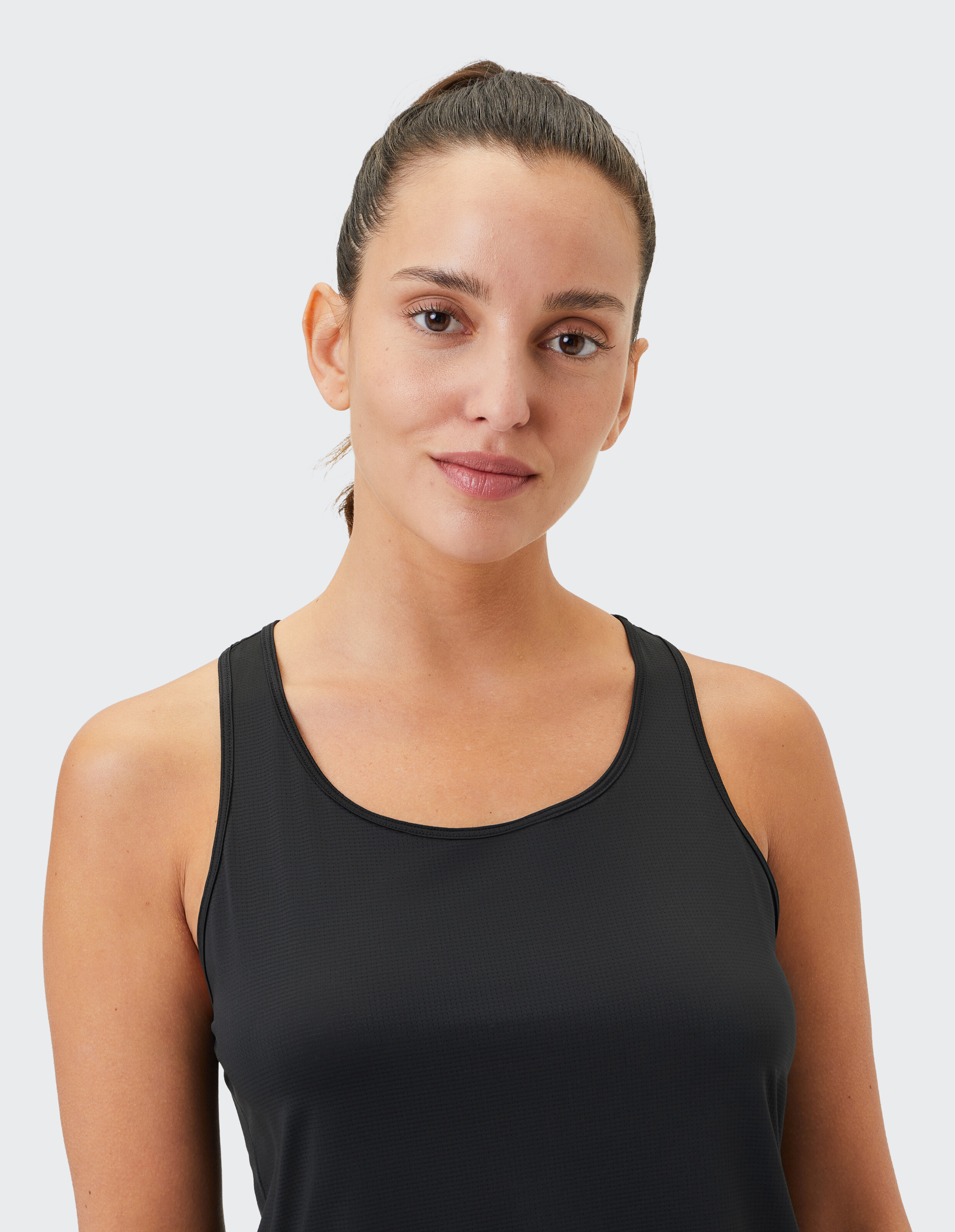 Frau trägt ein schwarzes Racerback-Tanktop für lässige, bequeme Alltagskleidung.