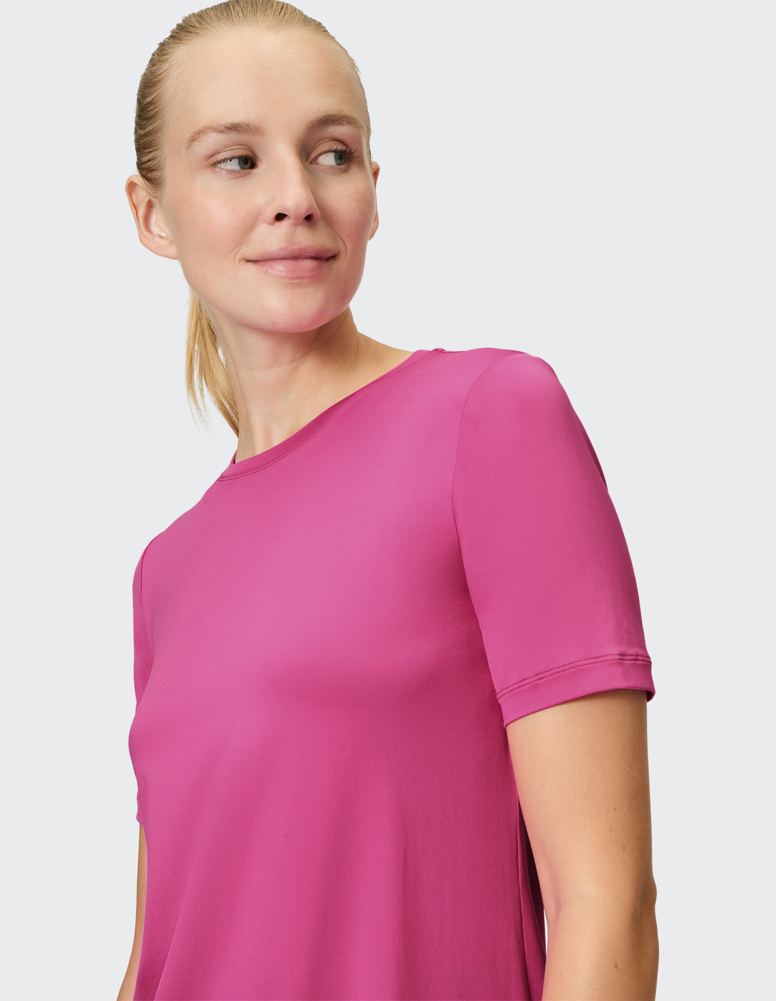 Frau trägt ein kurzärmliges rosafarbenes Oberteil und präsentiert einen lässigen und stilvollen Look.