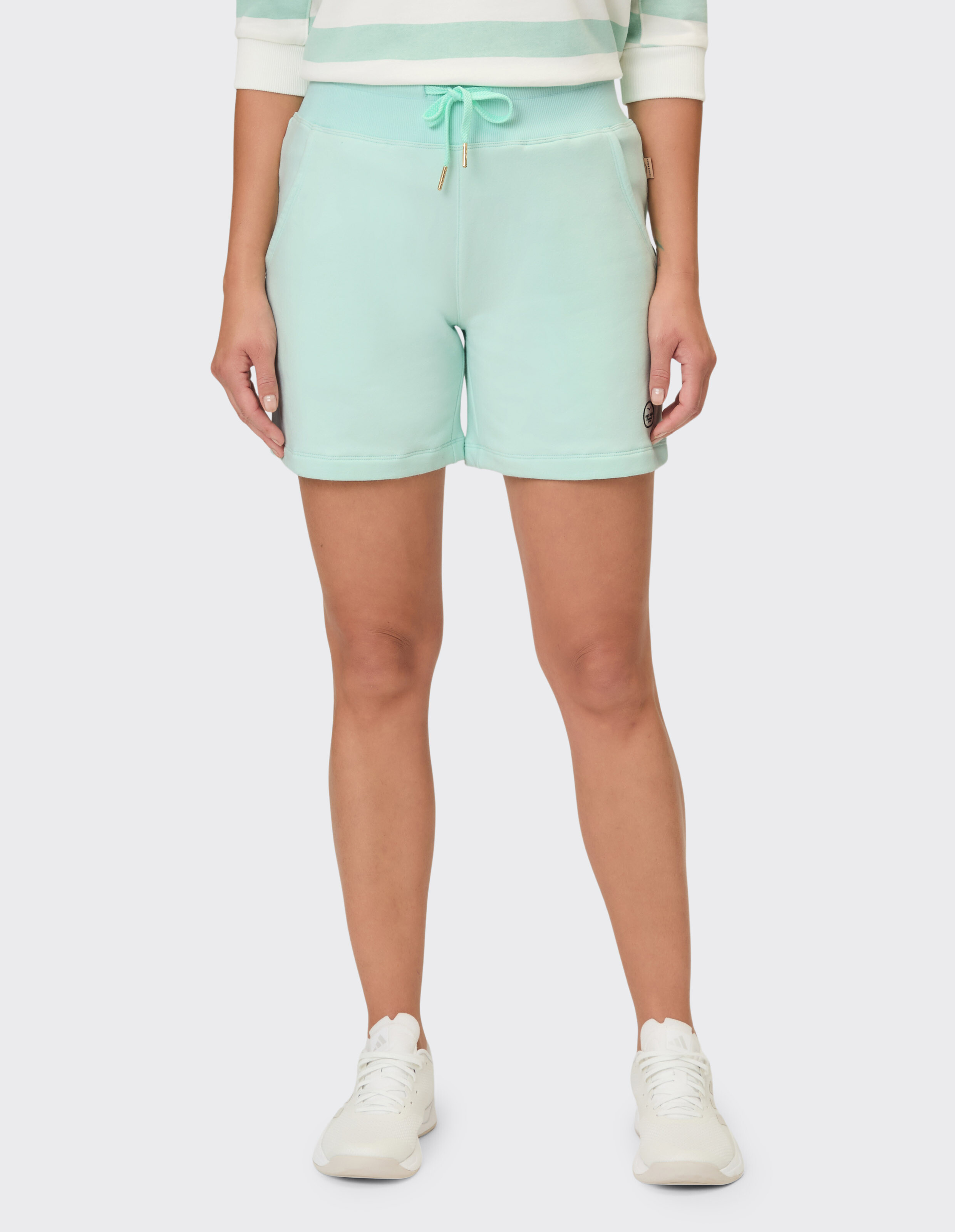 Frau trägt mintgrüne, lässige Sweatshorts mit Kordelzug in der Taille.
