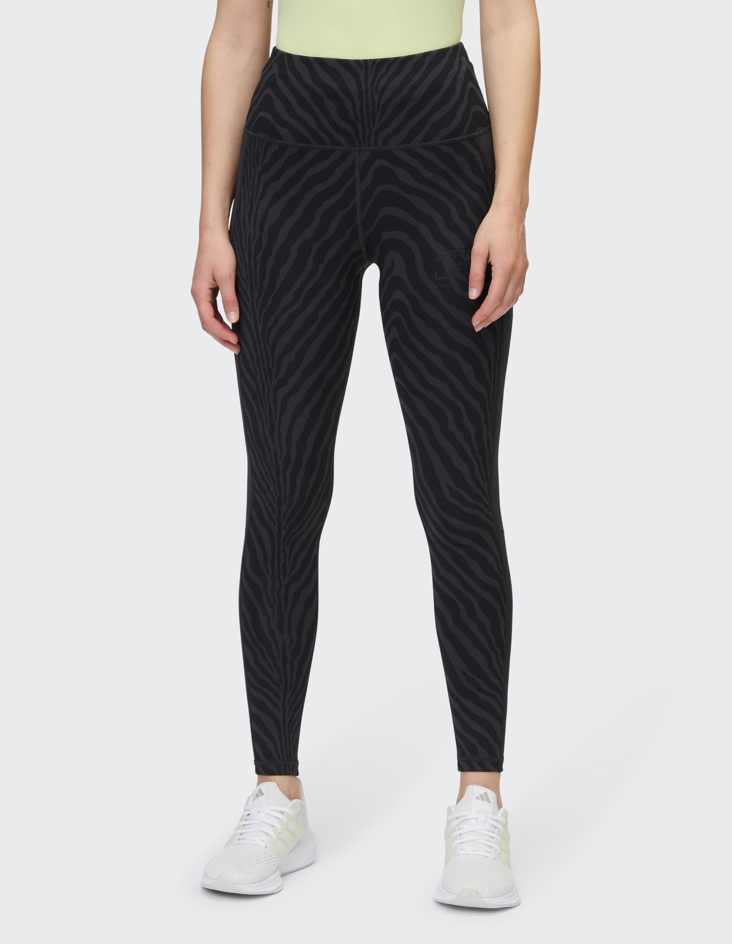 Frau trägt schwarze Leggings mit hohem Bund und dezentem Zebramuster für lässigen Komfort.