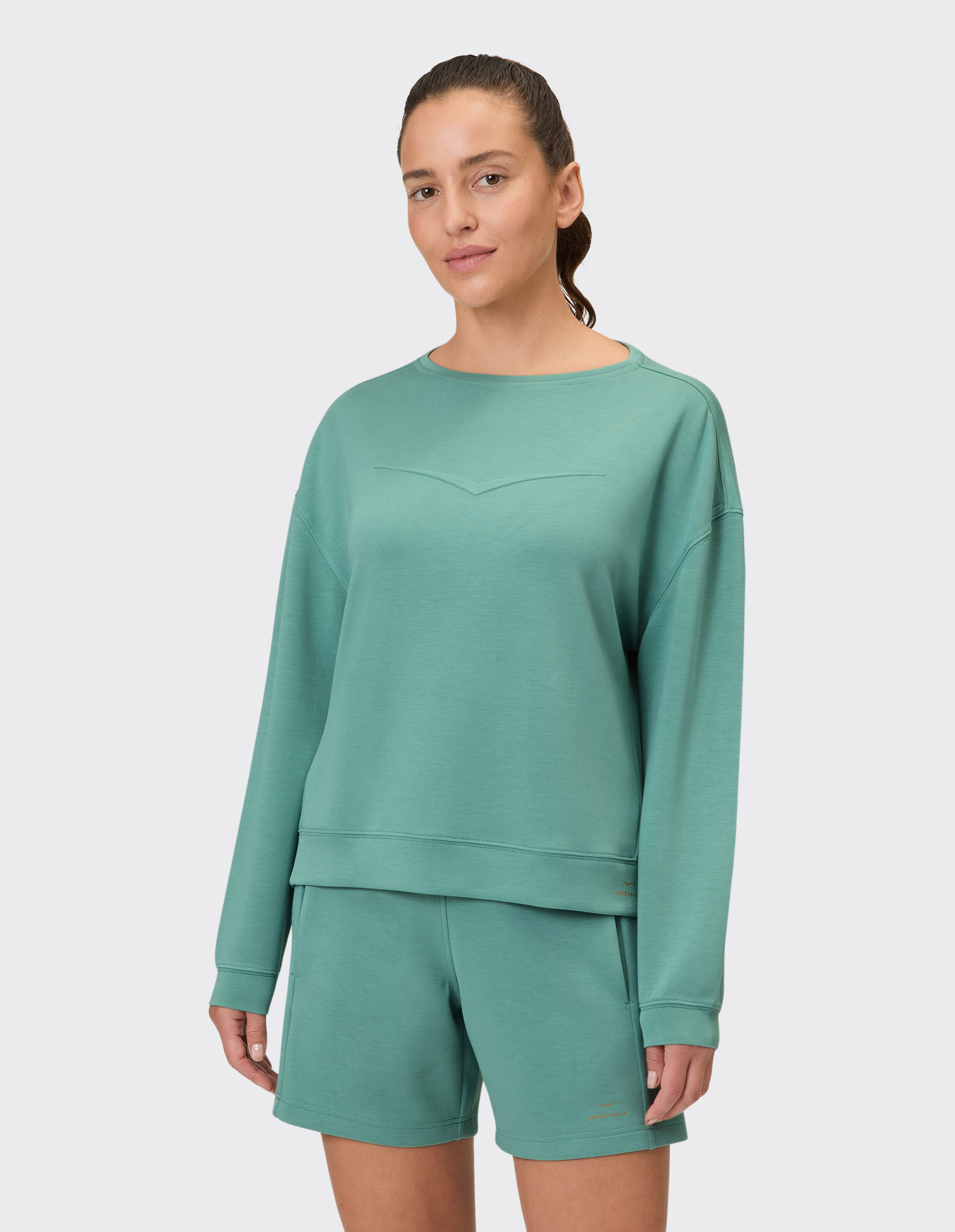 Frau trägt ein gemütliches grünes Venice Beach April-Sweatshirt für einen lässigen Lounge-Stil.